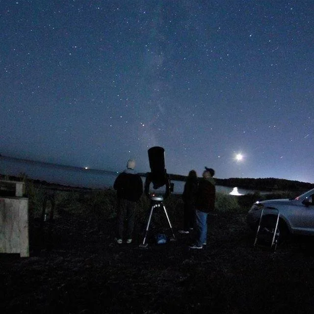 People stargazing by a bay with a telescope