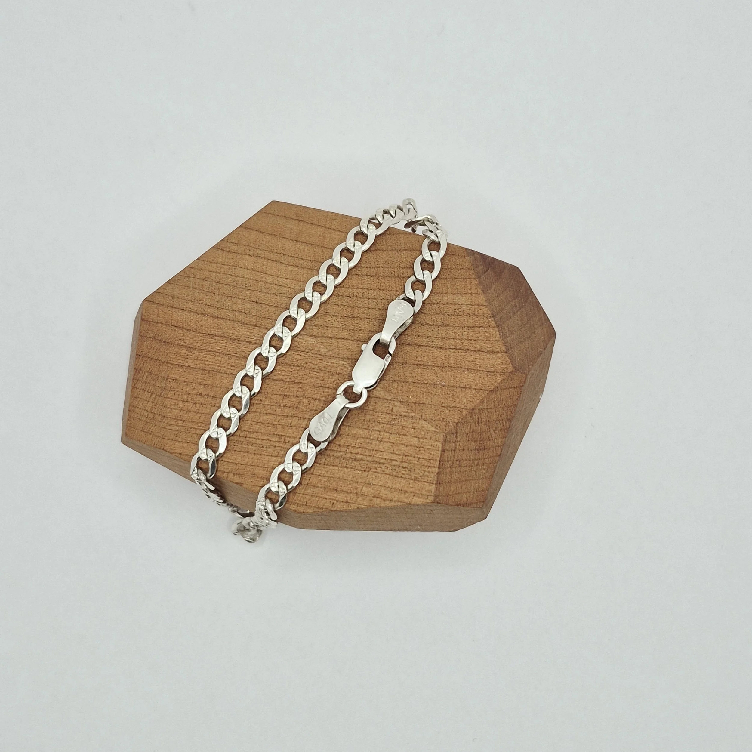 2️⃣ Close-up of sterling silver curb chain bracelet clasp, minimalist design
