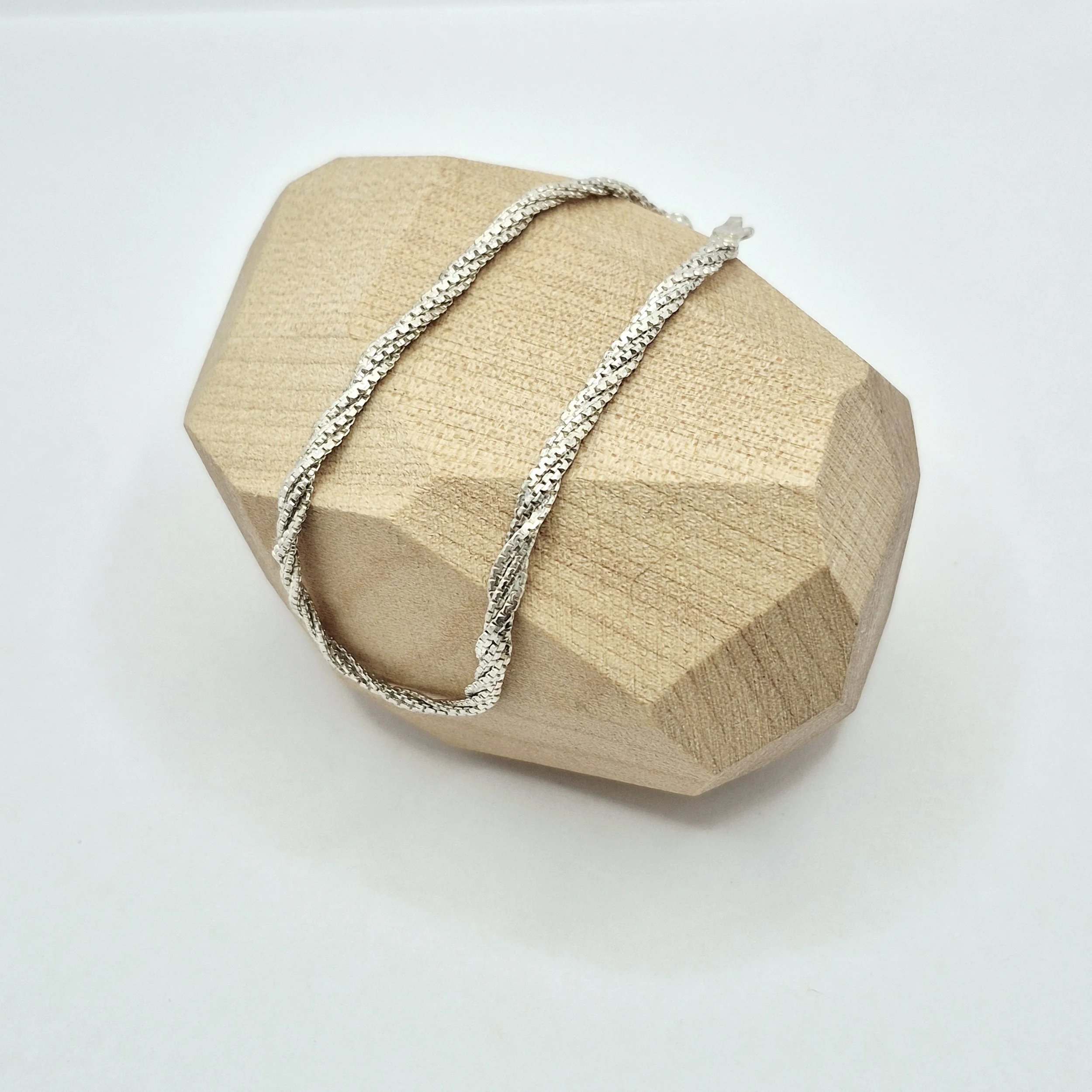 2️⃣ Textured silver serpentine bracelet laying flat on display