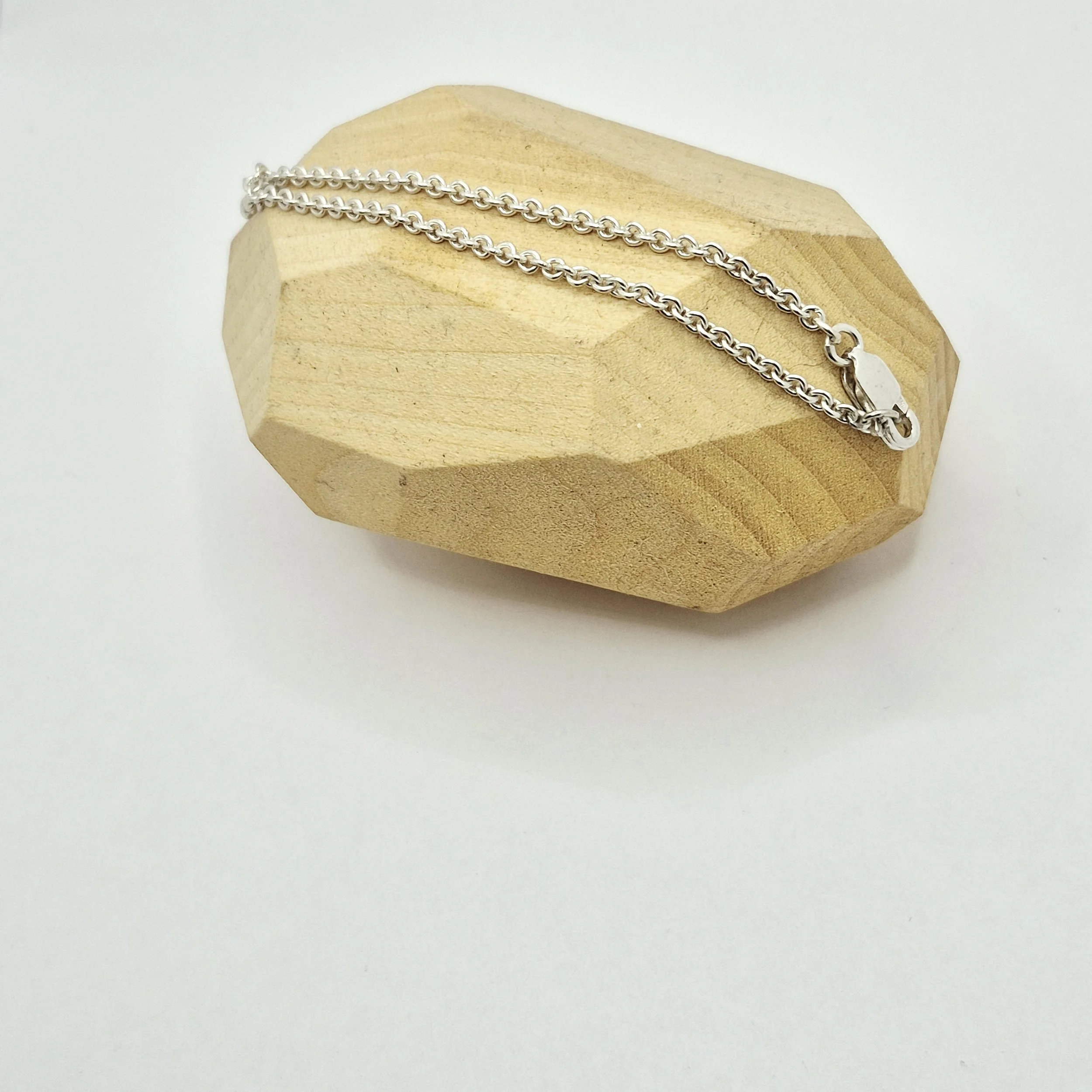 3️⃣ Long silver bracelet or anklet on geometric wood stand