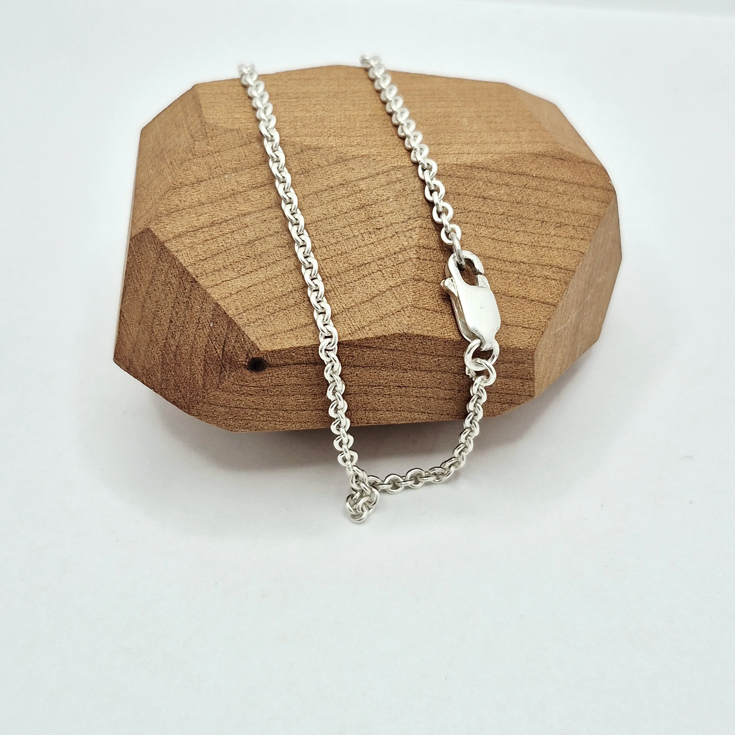 Delicate silver rope bracelet with lobster clasp on wood jewelry display
