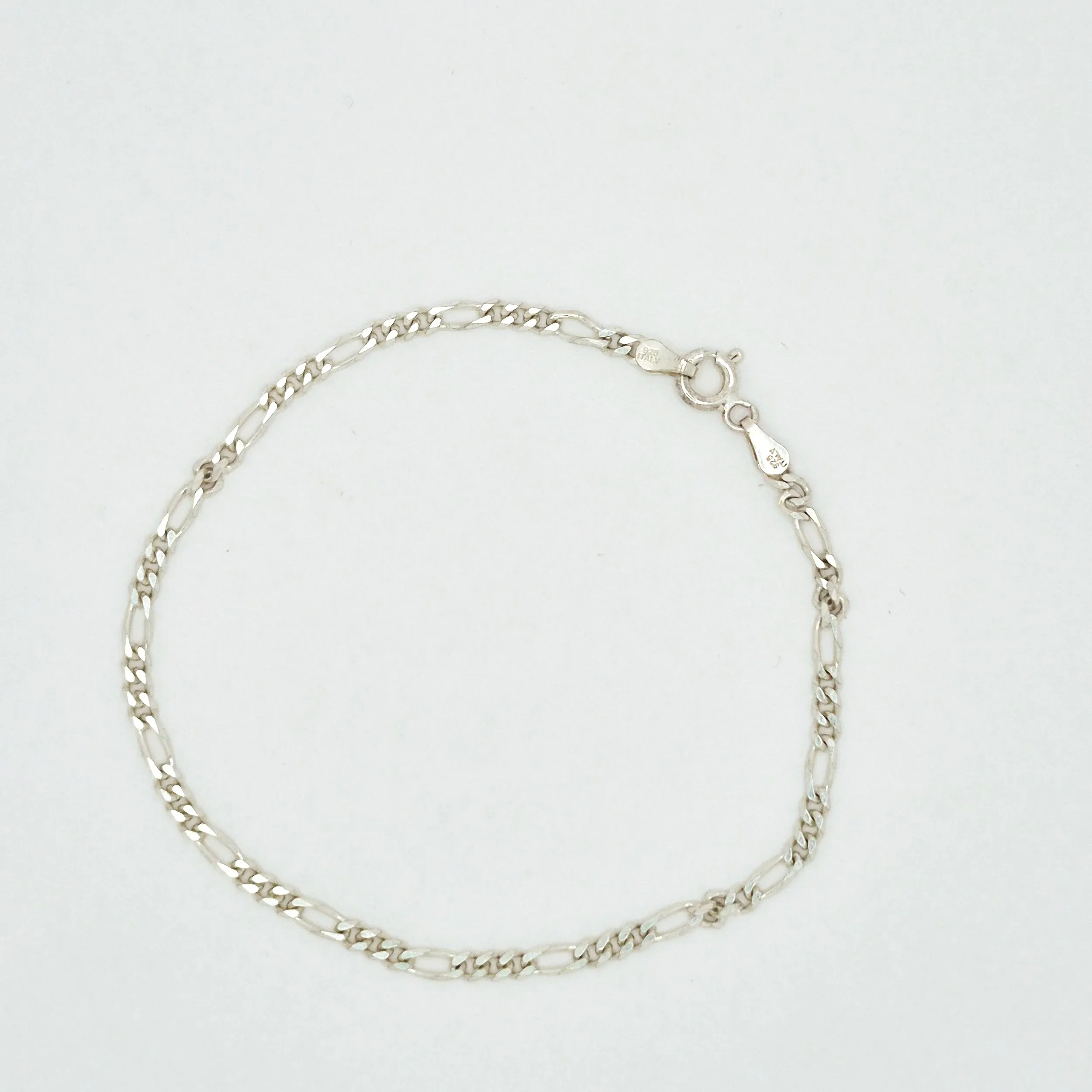 3️⃣ Simple silver Figaro bracelet resting on wood background