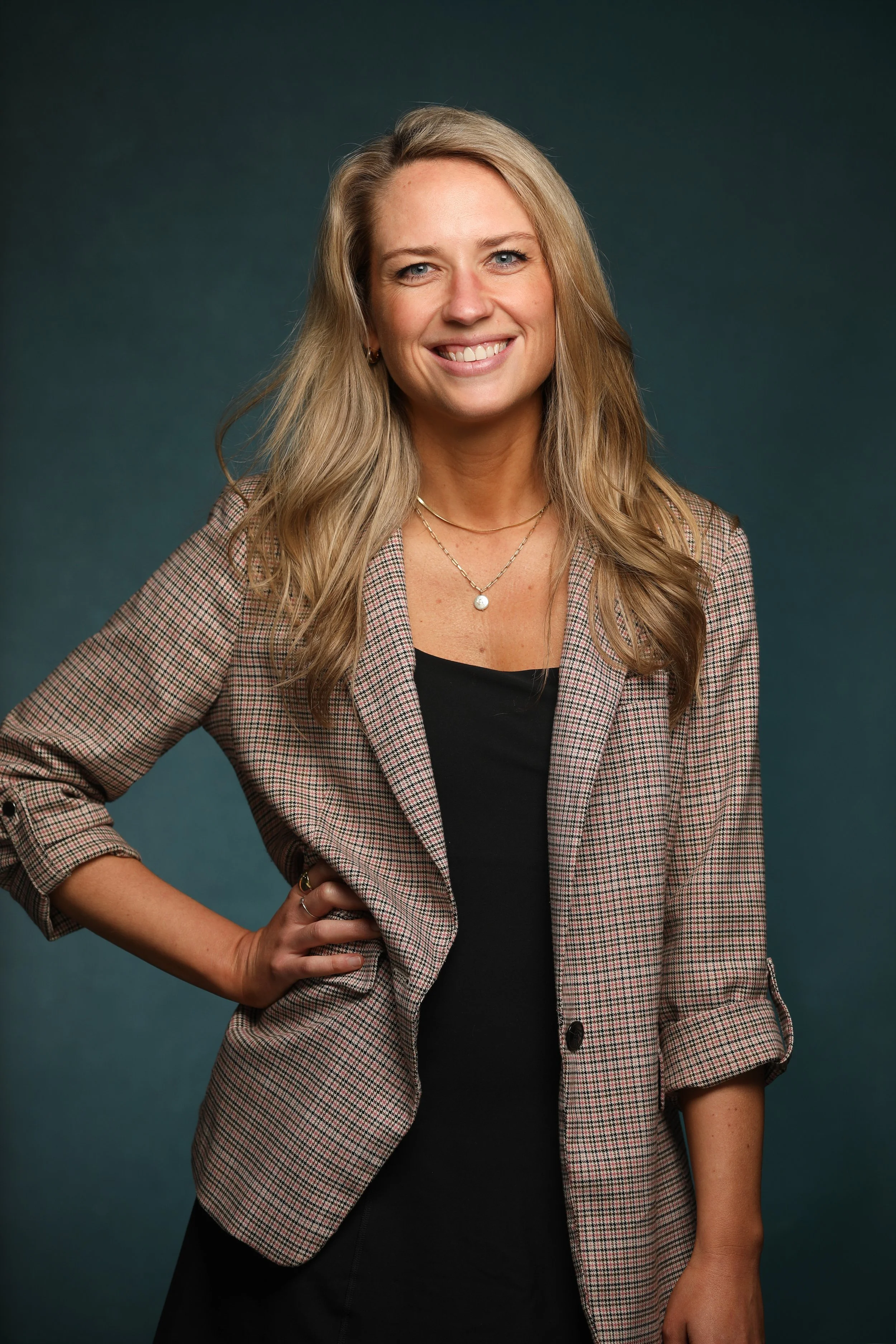 Laura Allen standing in suit blazer with hand on hip
