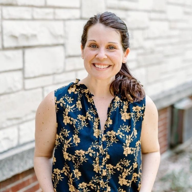 Betsy Barnich smiling in front of a brick wall