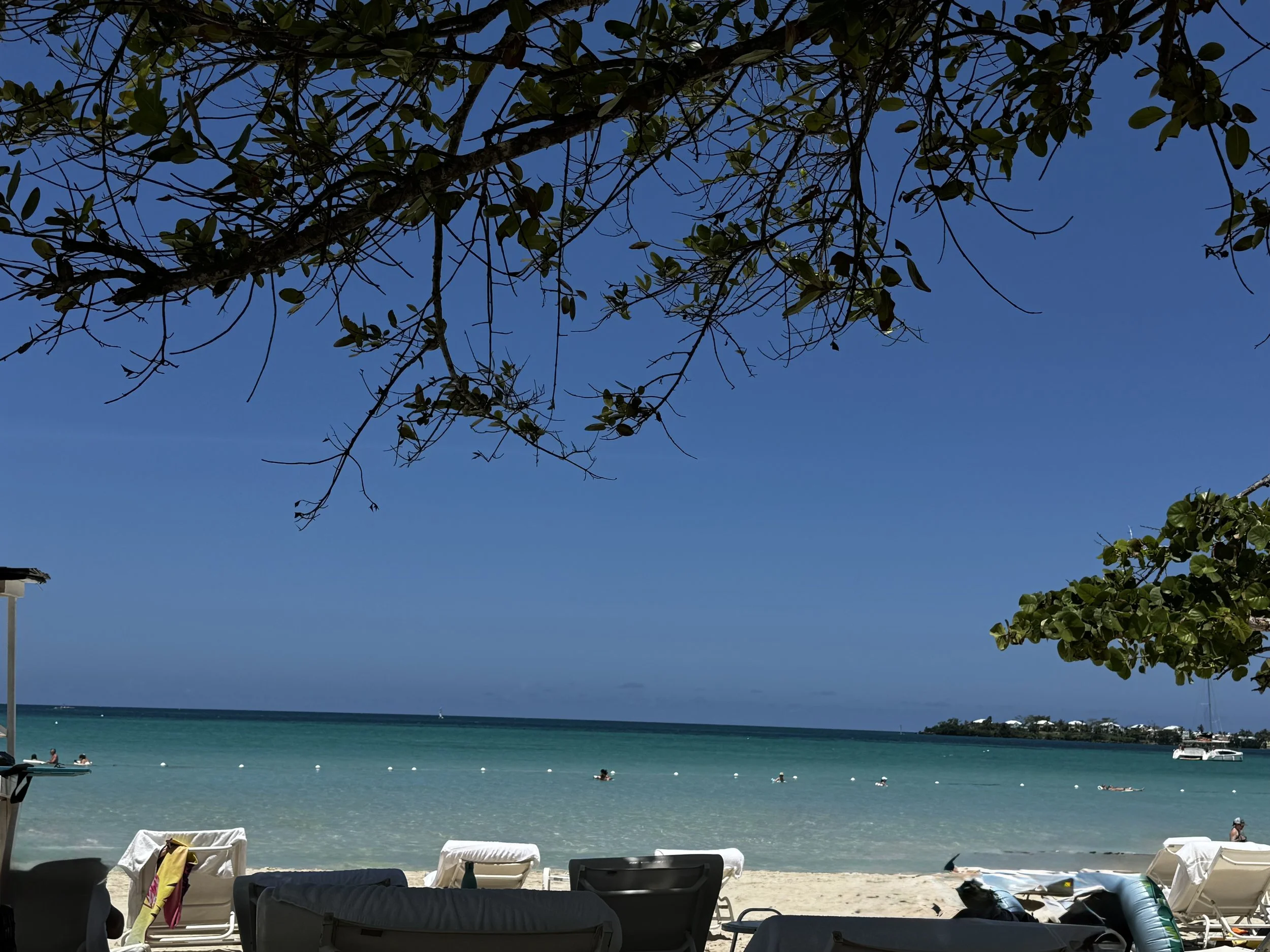 Beach view with clear turquoise water and lounge chairs at Couples Negril resort in Jamaica