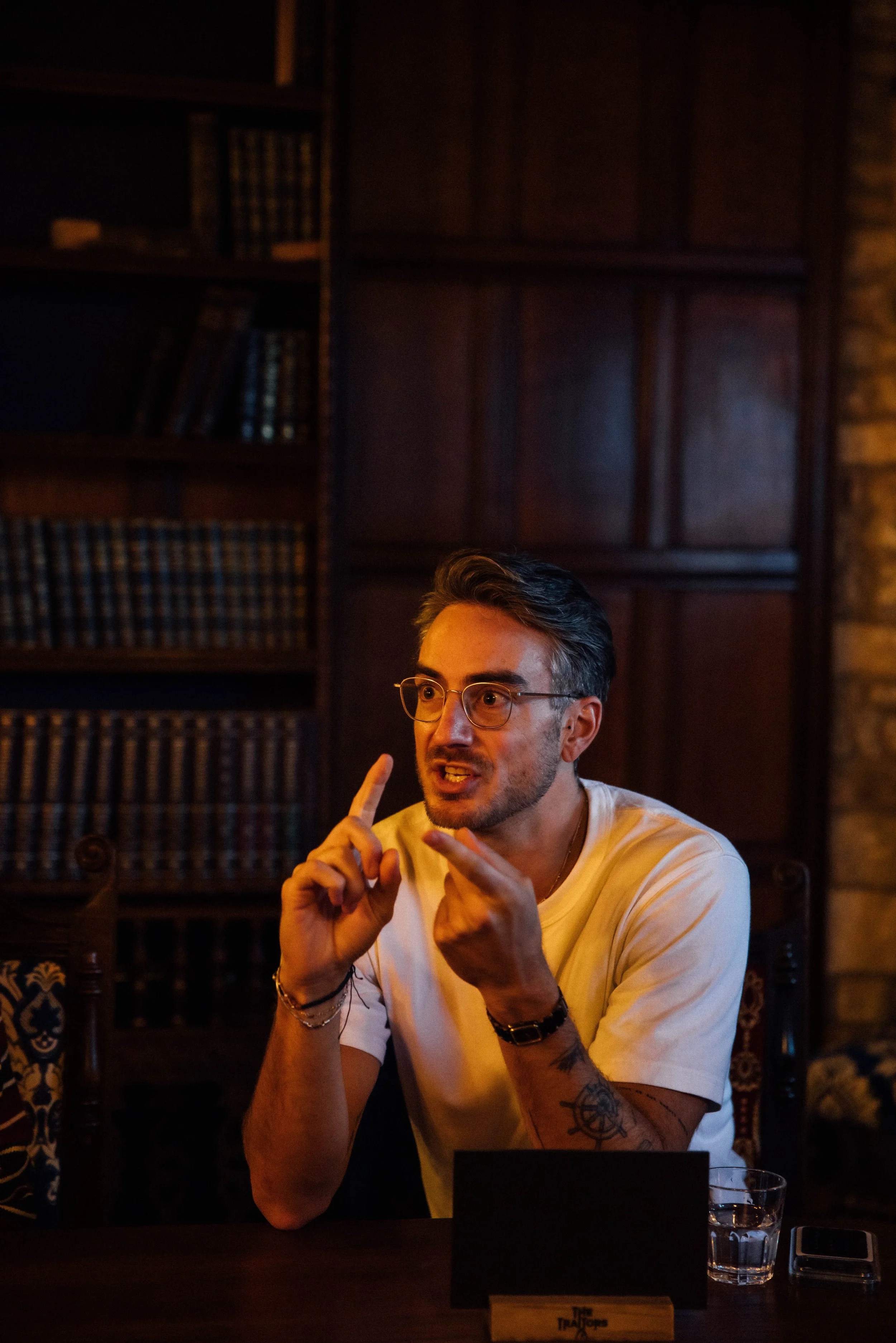 Player leading a round table discussion at TikTok’s Traitors experience, speaking with expressive hand gestures during the live event.