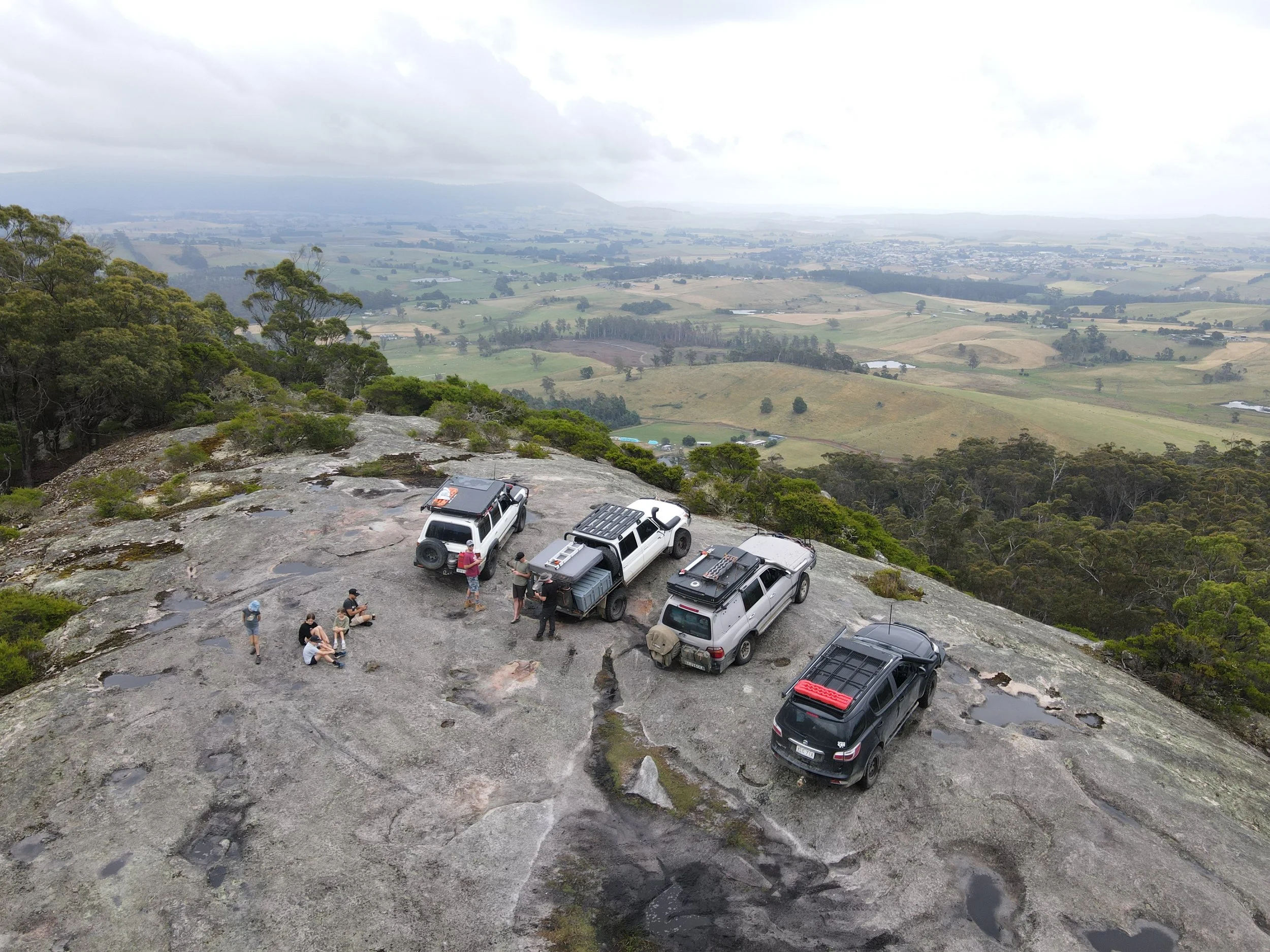 Four wheel drives parked on a rocky lookout overlooking Tasmanian farmland