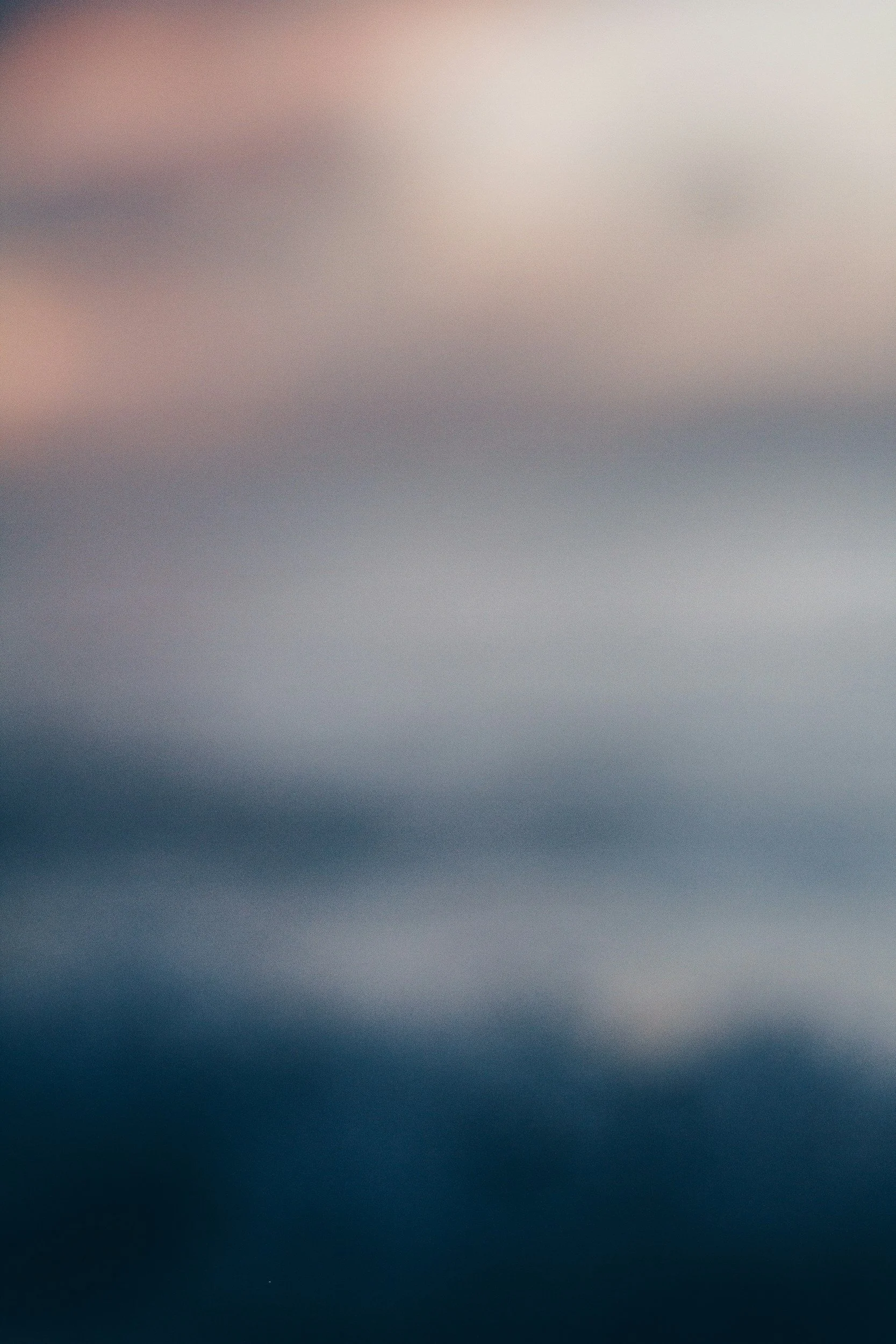 The image is blurred with shades of pink, blue, and gray, making it difficult to identify specific objects or scene.