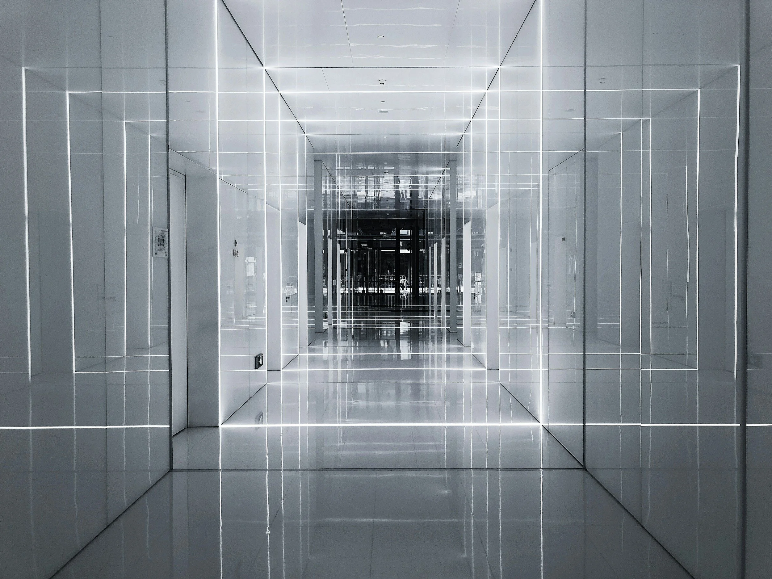 A futuristic hallway with reflective white walls and ceiling, and LED light strips outlining the edges, creating a tunnel effect.