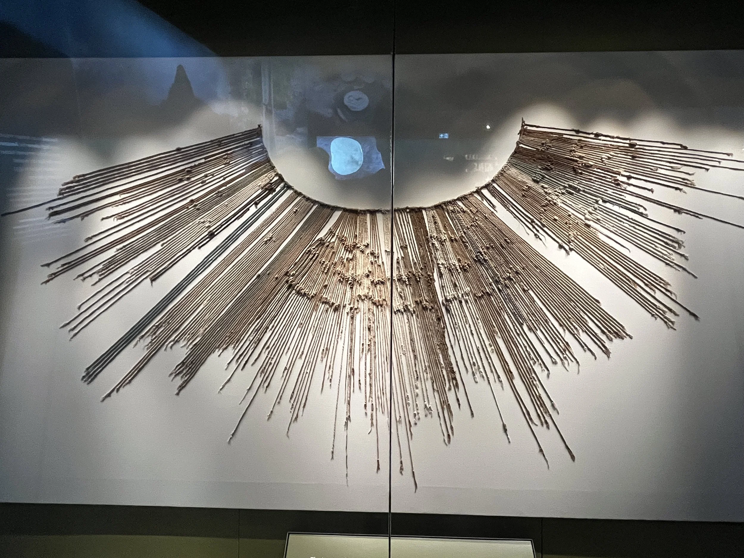Ancient copper necklace with radiating linear design displayed in a museum exhibit.