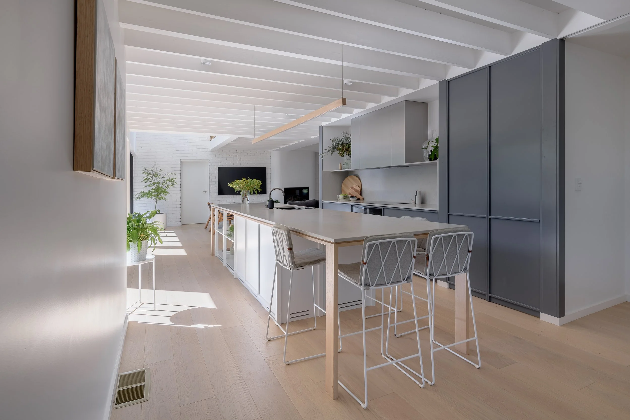 Kitchen in Castlepeake Architects Riverview house, grey cabinetry, light wooden floors, timber exposed beam ceiling