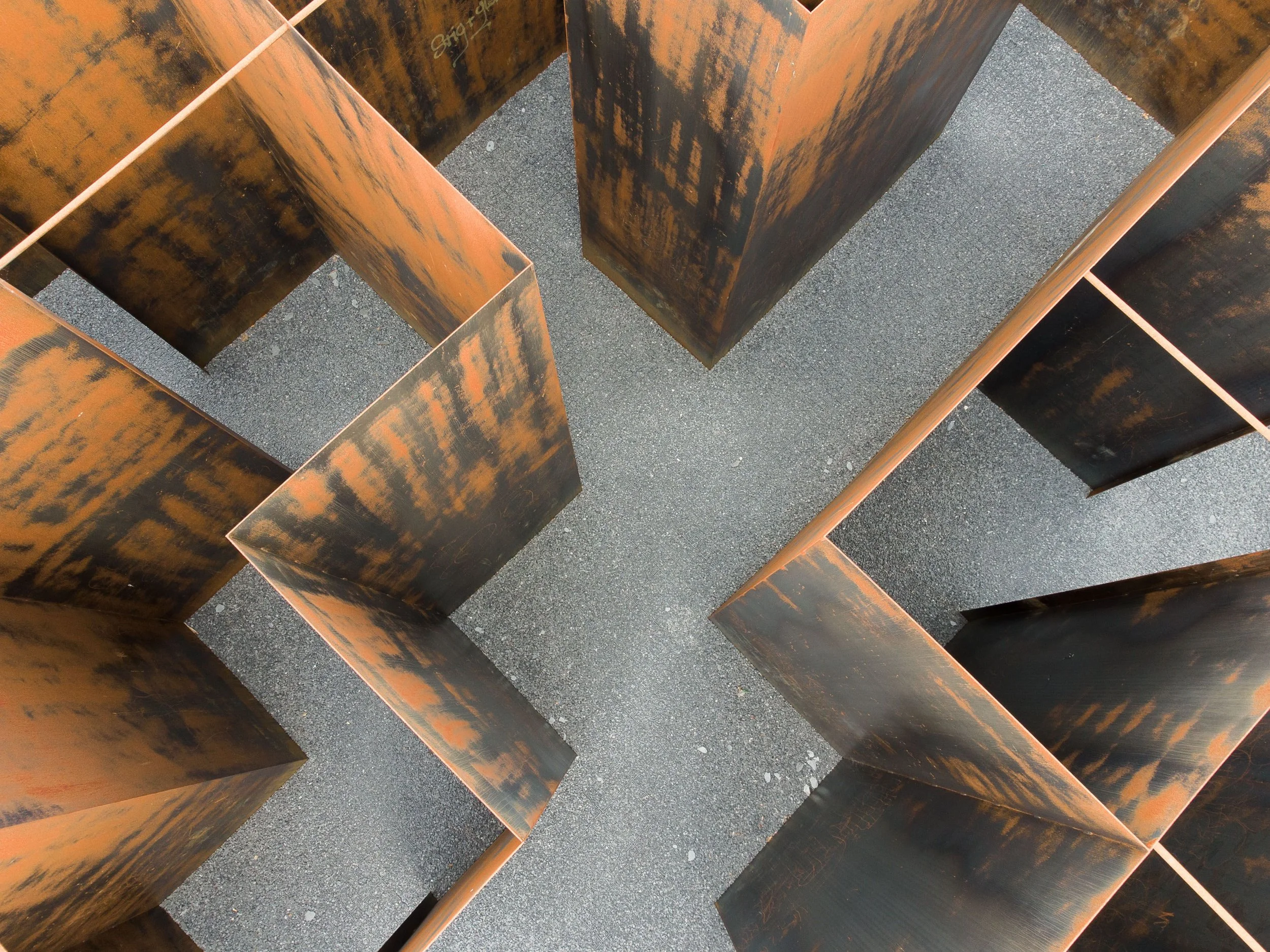 Specialtillverkade detaljer i cortenstål på mått med naturlig rostpatina, fotograferade ovanifrån i geometriskt mönster.