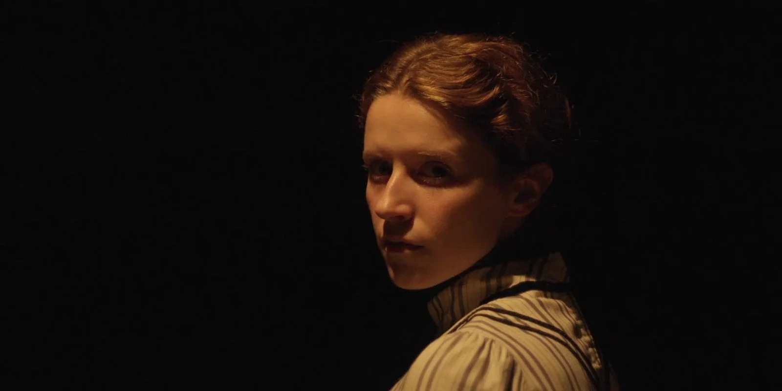 Da Gesicht von Paula schwach beleuchtet vor schwarzem Hintergrund