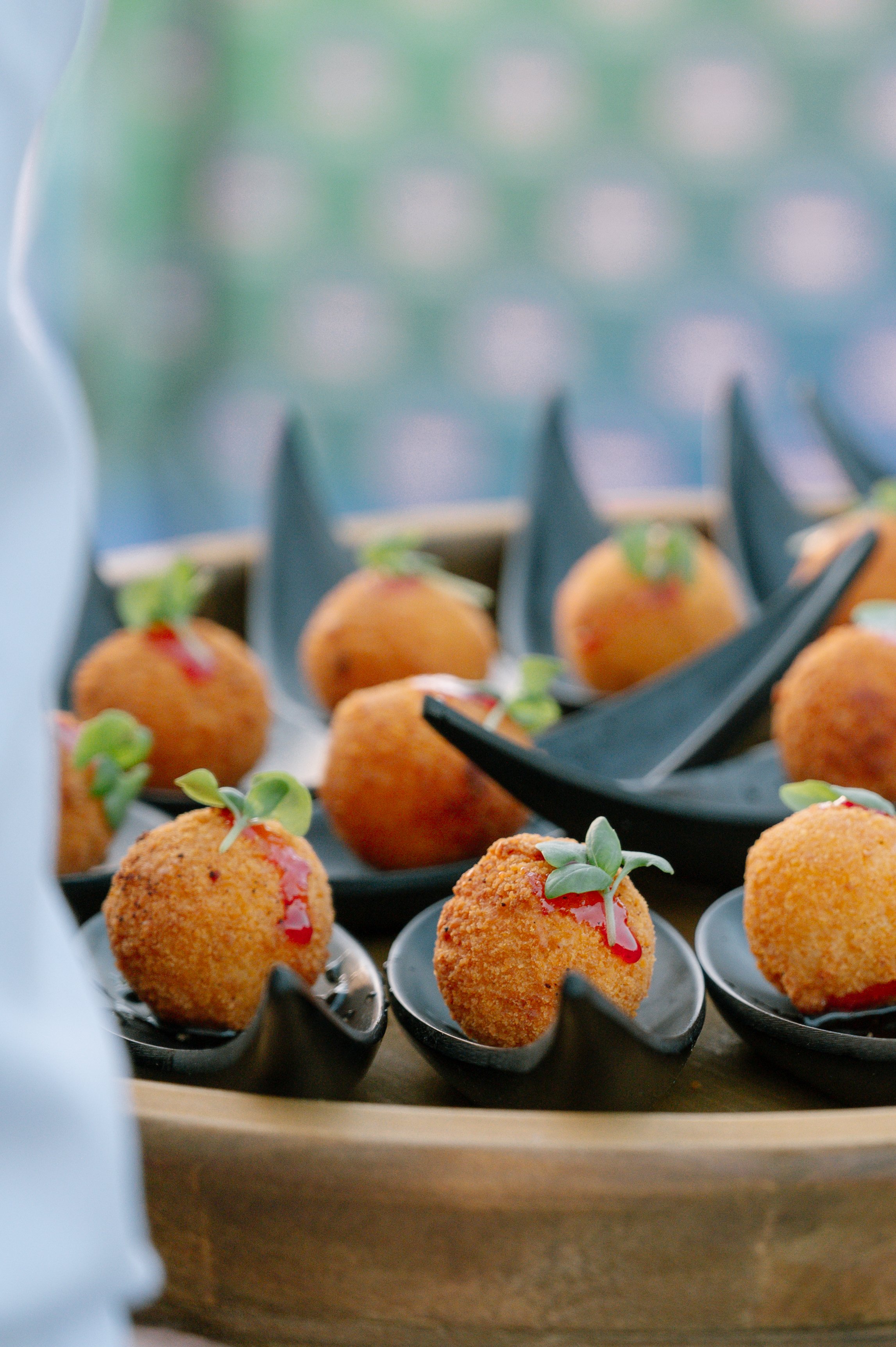Coconut-fried appetizers garnished with microgreens served on small black plates
