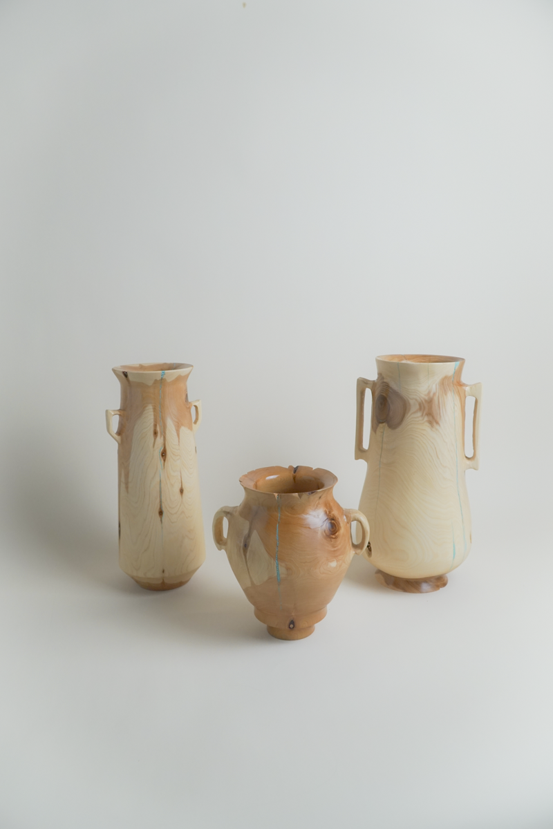 Three wooden vases with a natural wood grain pattern on a white surface against a plain white background.
