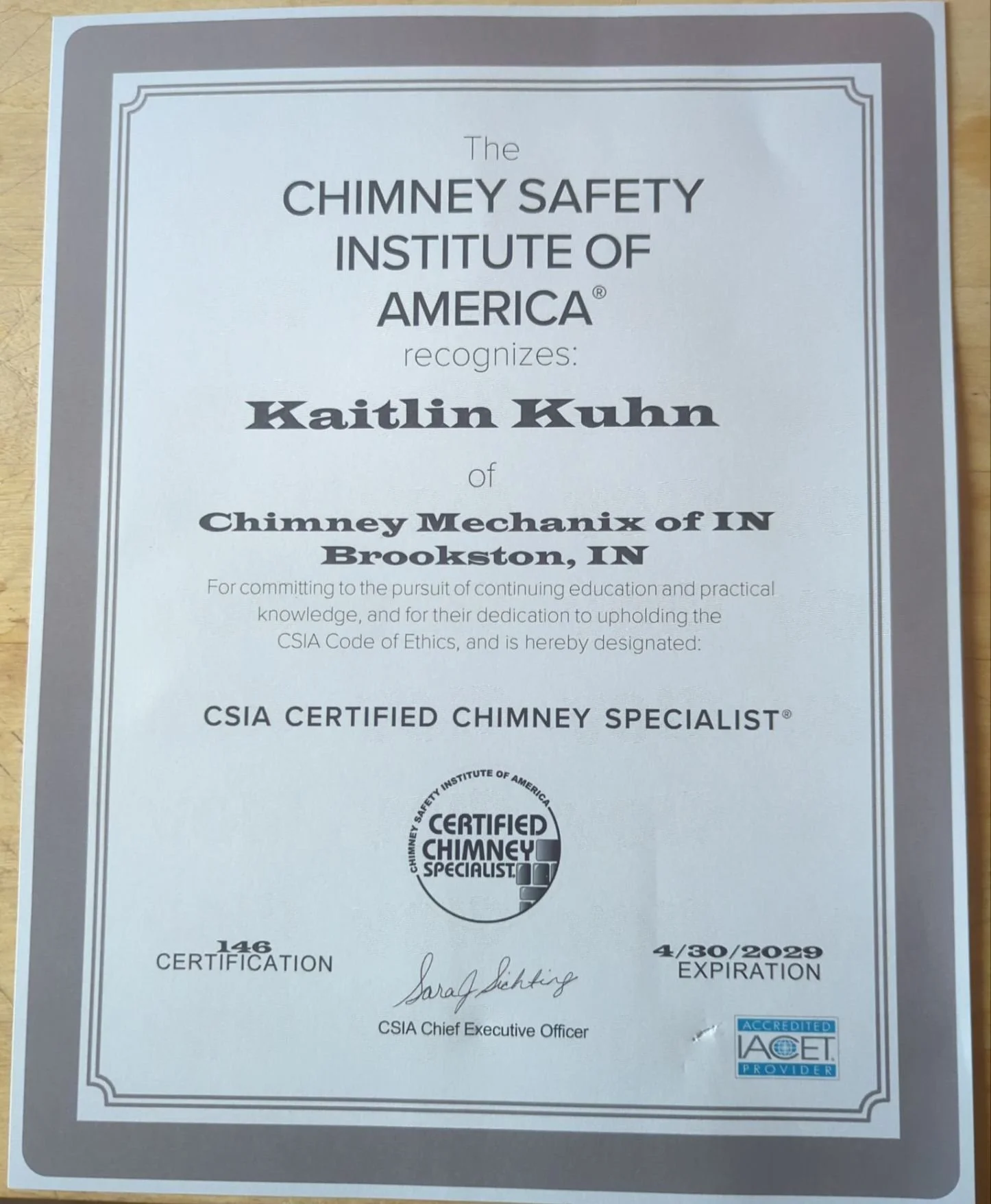 Certification plaque from the Chimney Safety Institute of America recognizing Kaitlin Kuhn as a CSIA Certified Chimney Specialist, issued on April 30, 2029, with signatures and official logos.