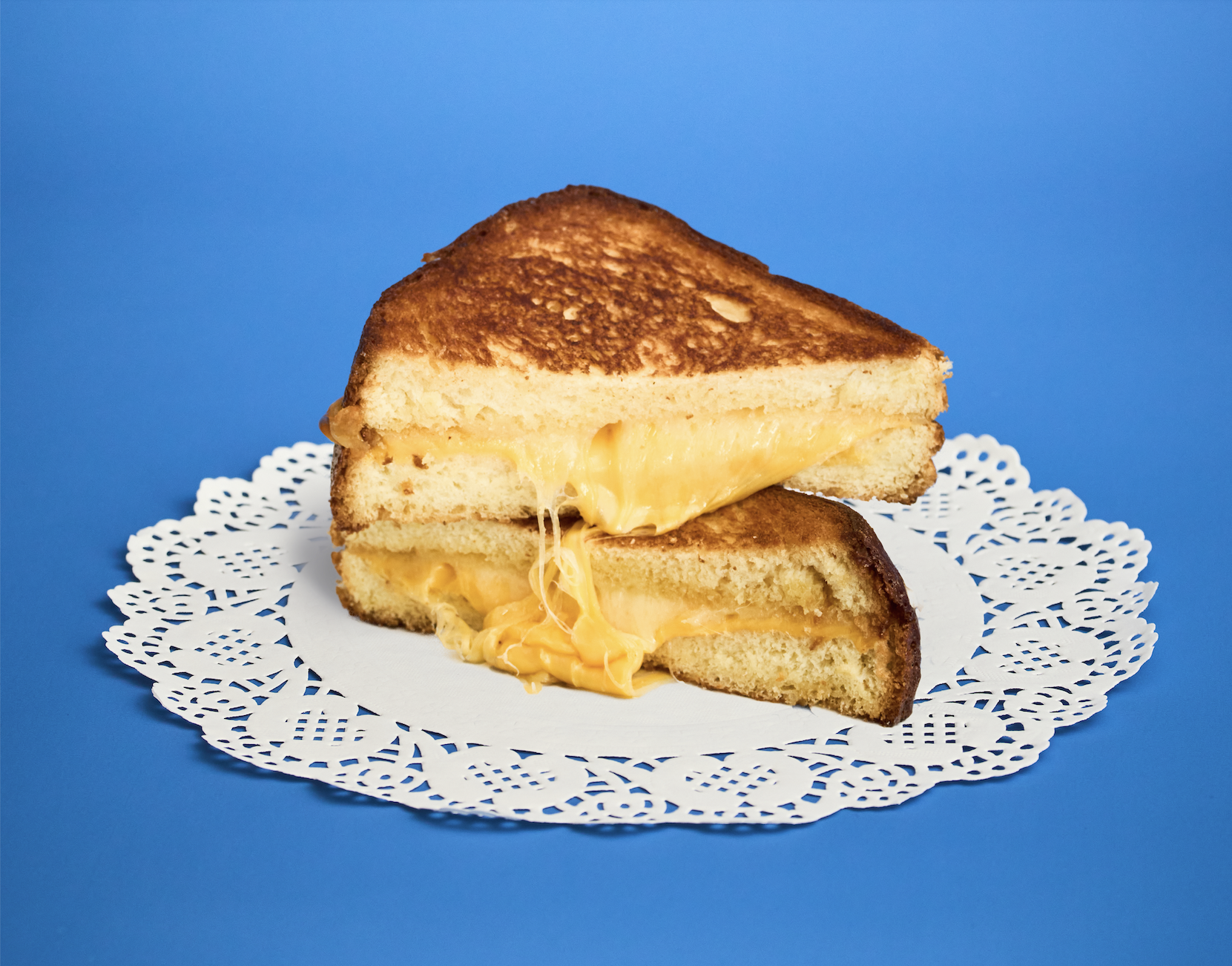 Our Grilled Cheese Sandwich features a classic cheese duo melted on butter toasted bread. This comfort food staple delivers rich, savory flavor and a crisp golden exterior.