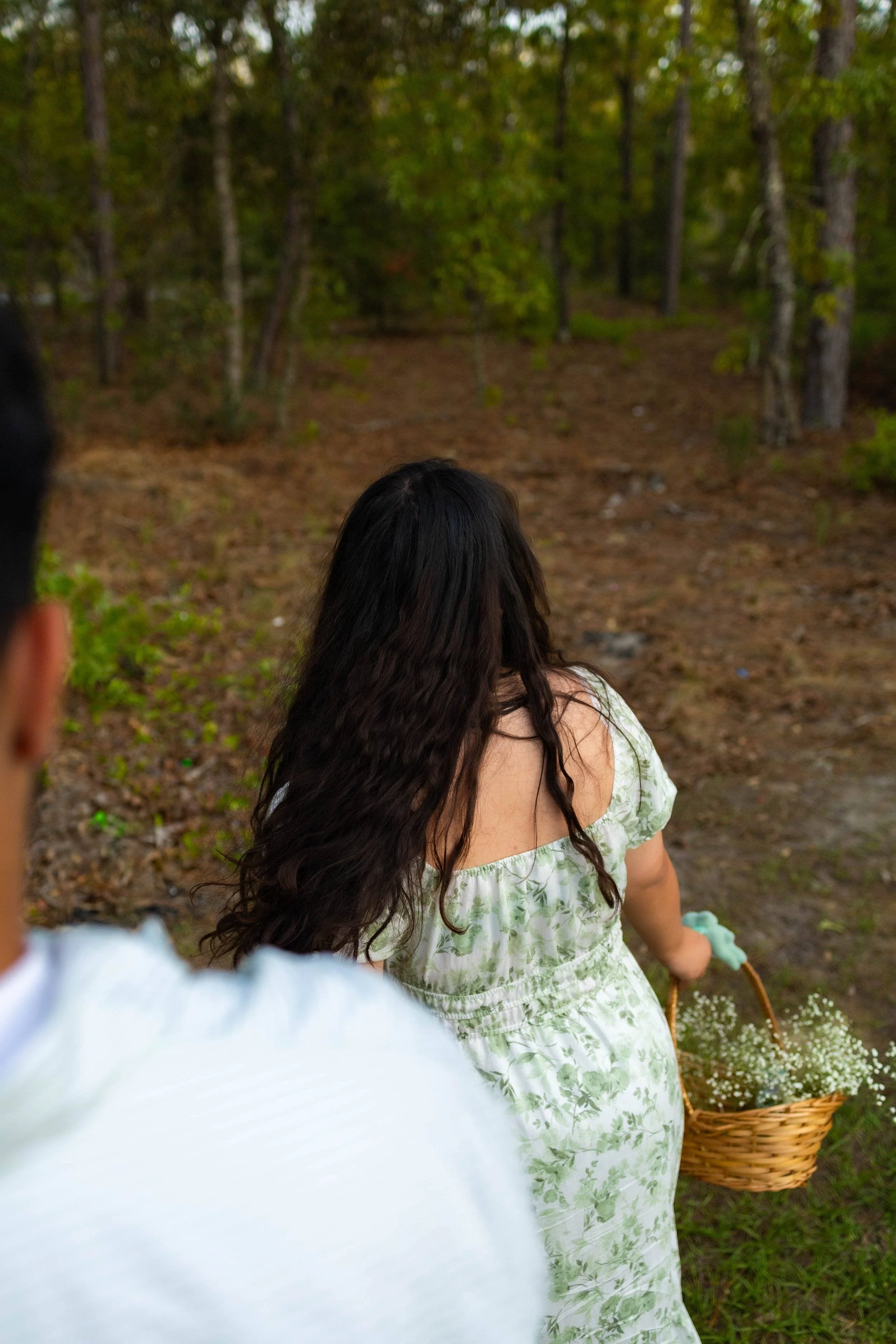 Young couple exploring the woods together picking flowers into a basket hand in hand. 