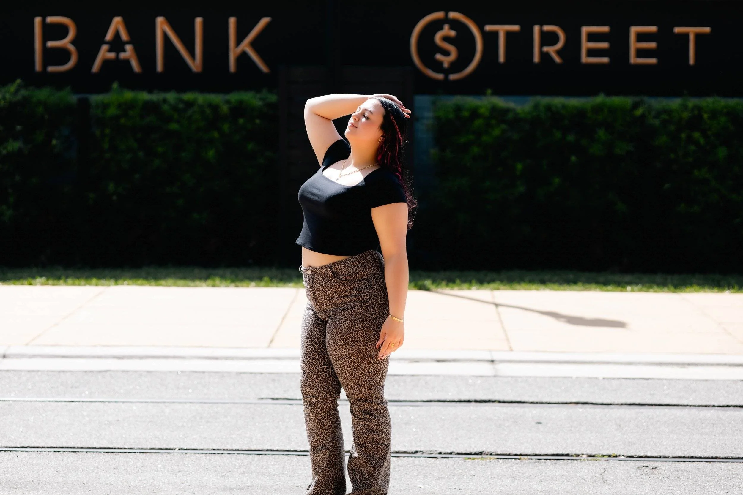 Young woman basking in the sun in the middle of a downtown street. the words bank street and the wall behind.