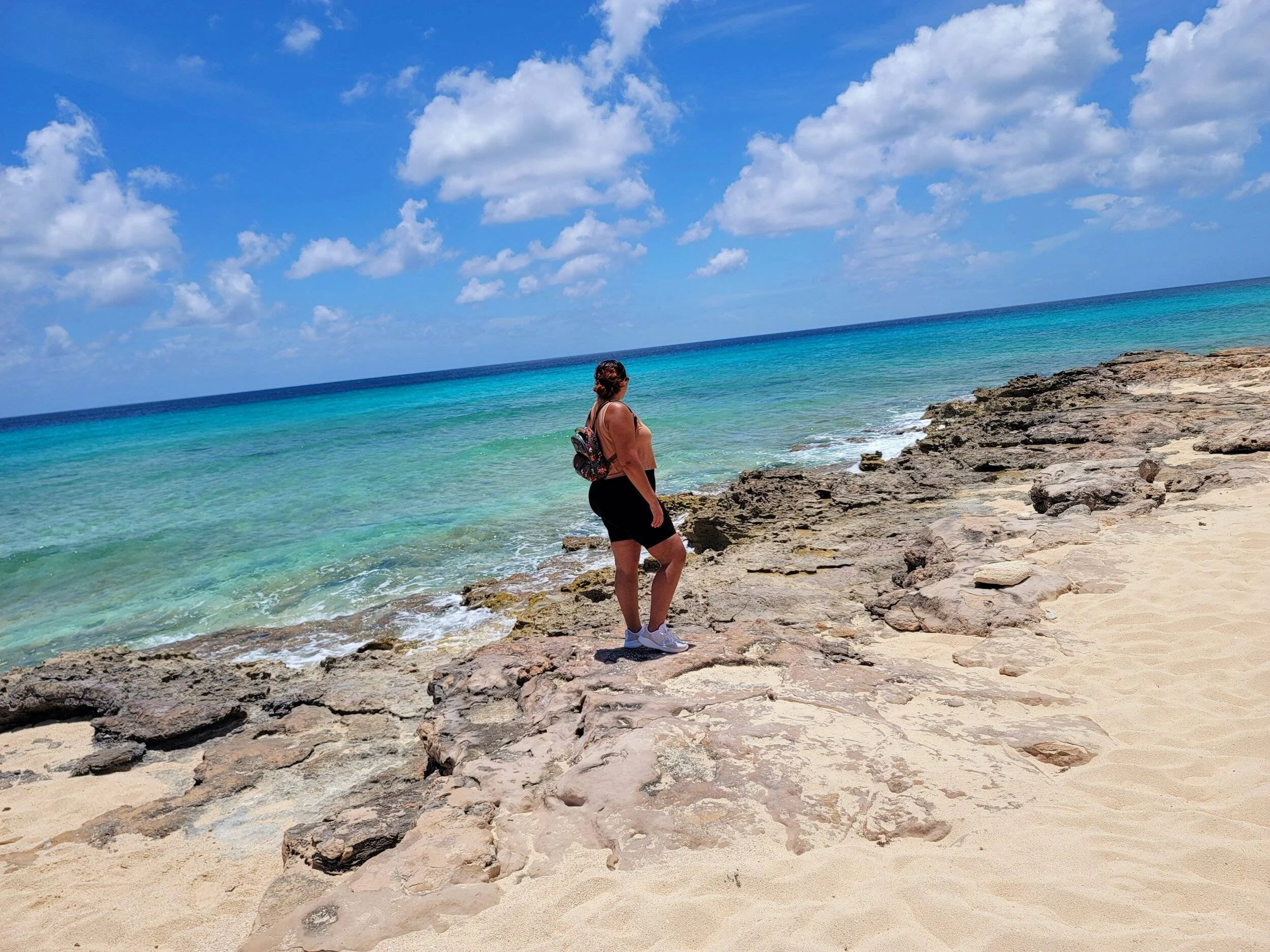 Woman standing on the beach admiring the ocean.