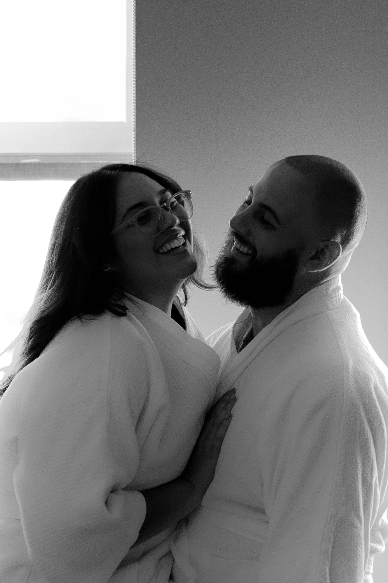 couple in  hotel robes celebrating anniversary smiling and laughing.