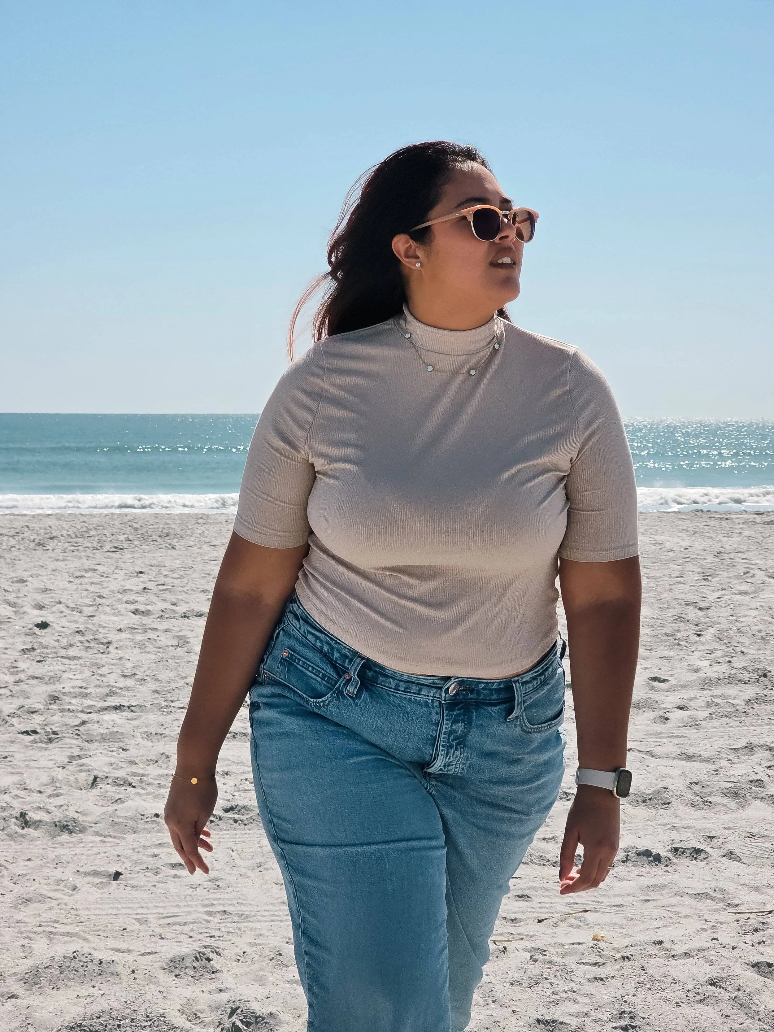 woman walking at the beach hair blowing in the wind.
