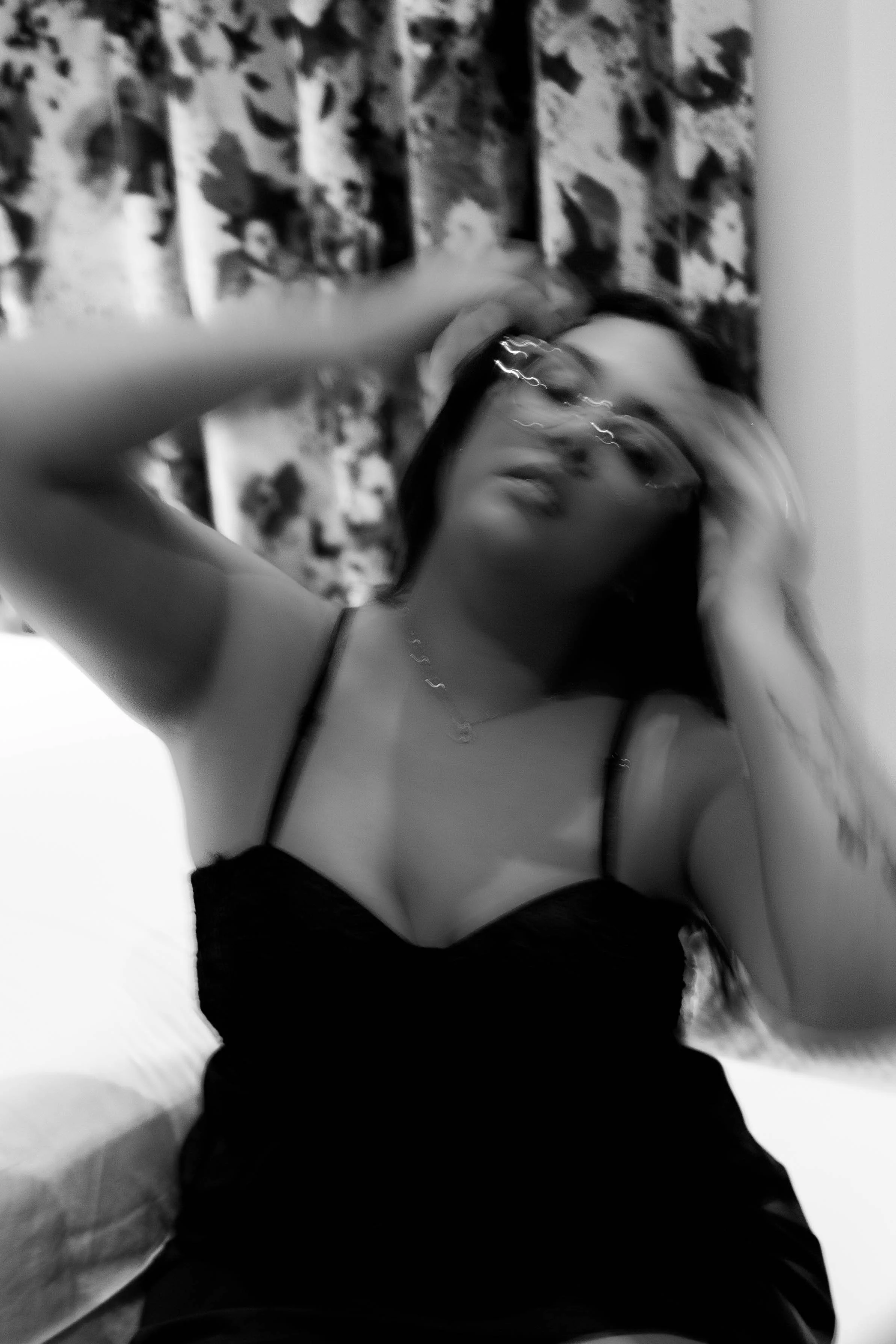 black and white image of women in hotel room fixing her hair.