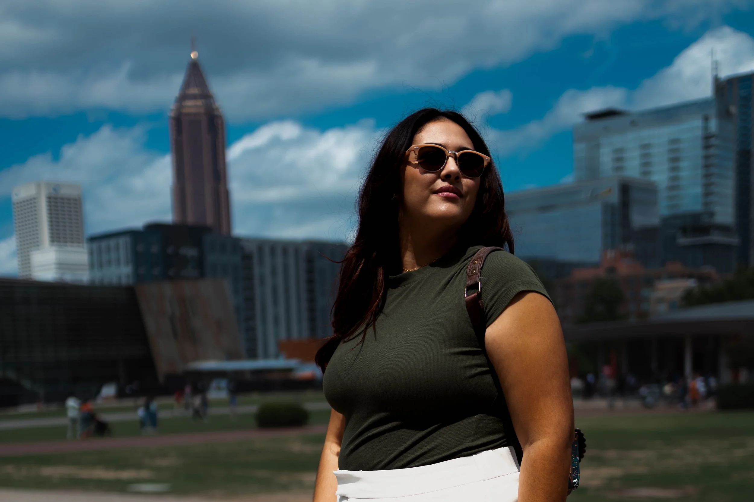 close up of a woman with sunglasses with e city scape in the background.