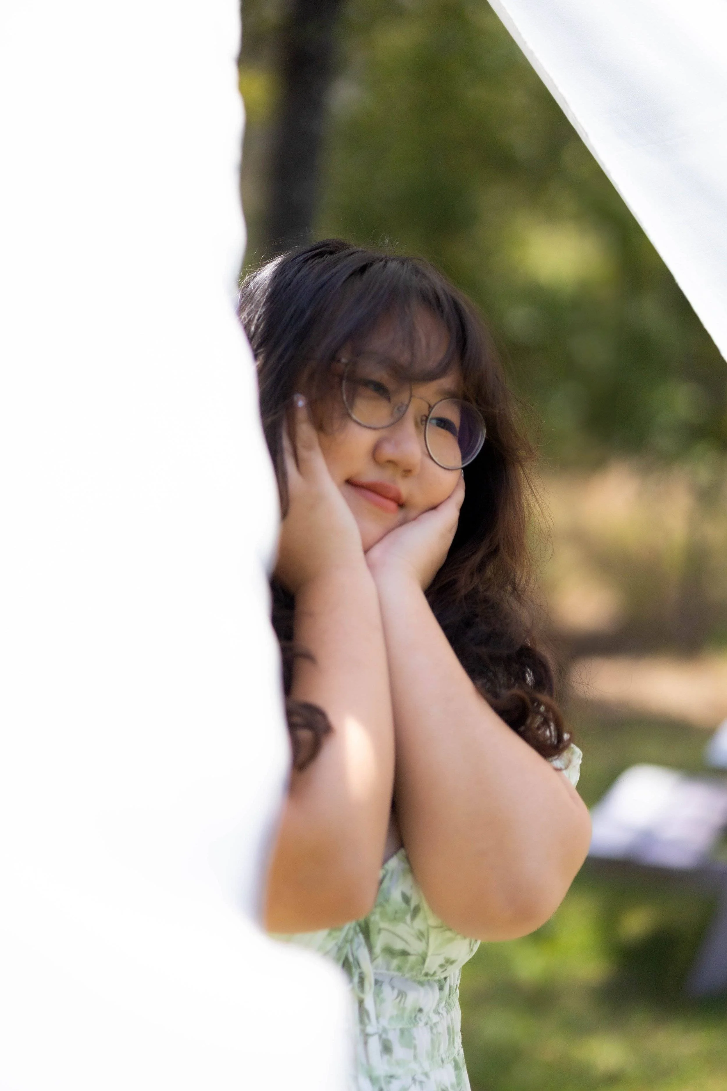 Girl looking shyly away in between hanging white sheets.