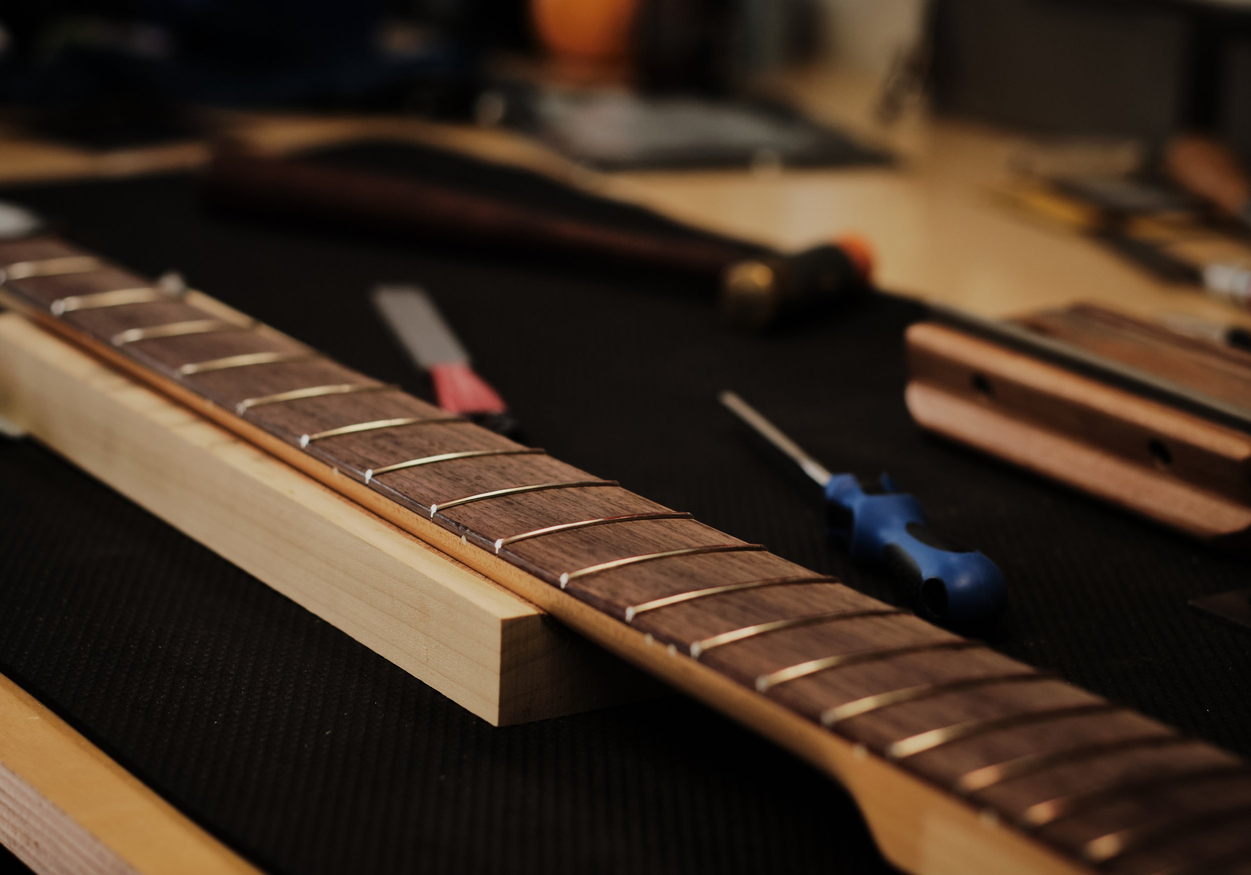 Guitar neck and fretboard on luthier workbench at Katsaros Guitars in Aptos CA