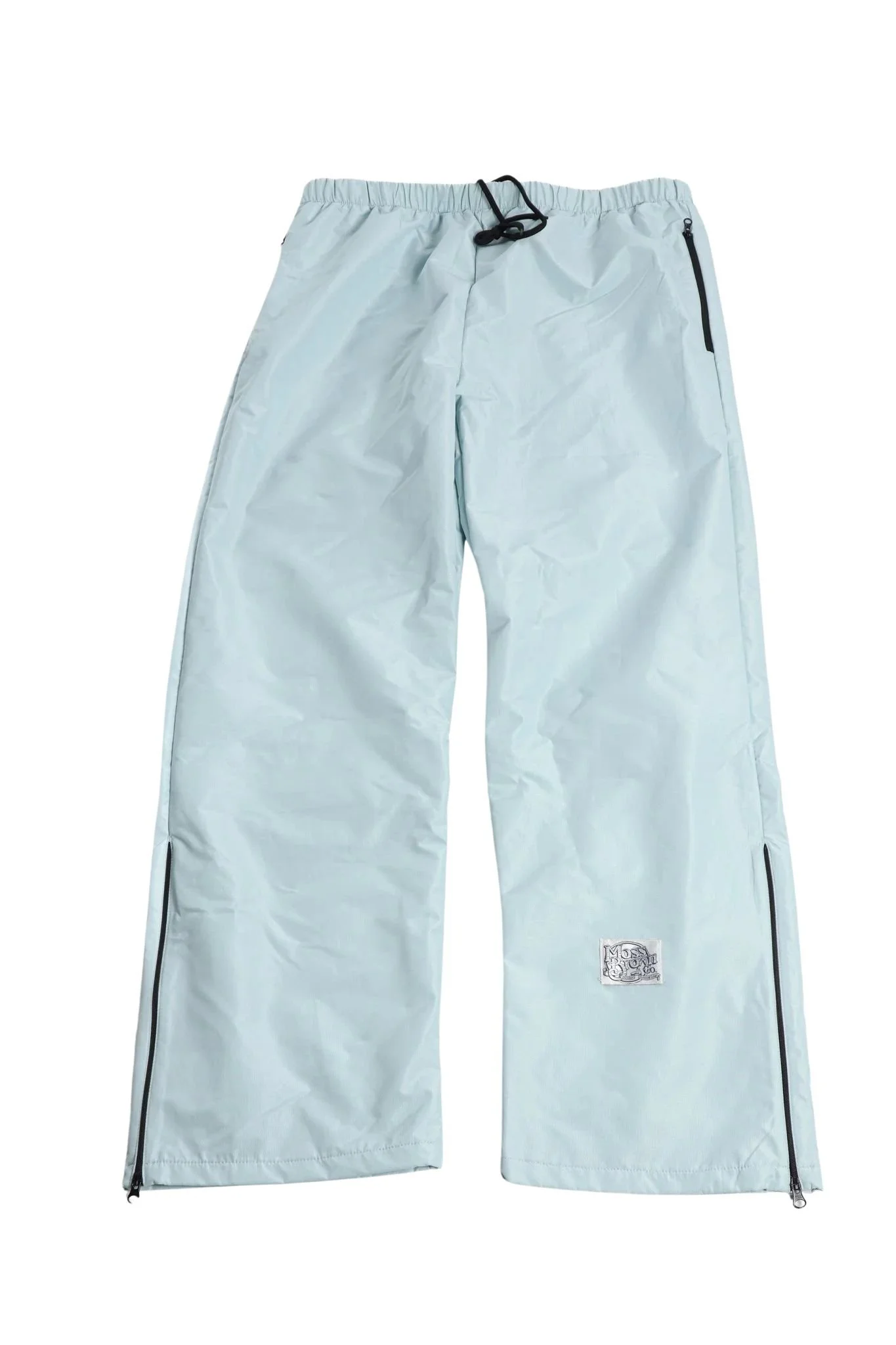 Black windbreaker pants hanging on a hanger against a plain wall.