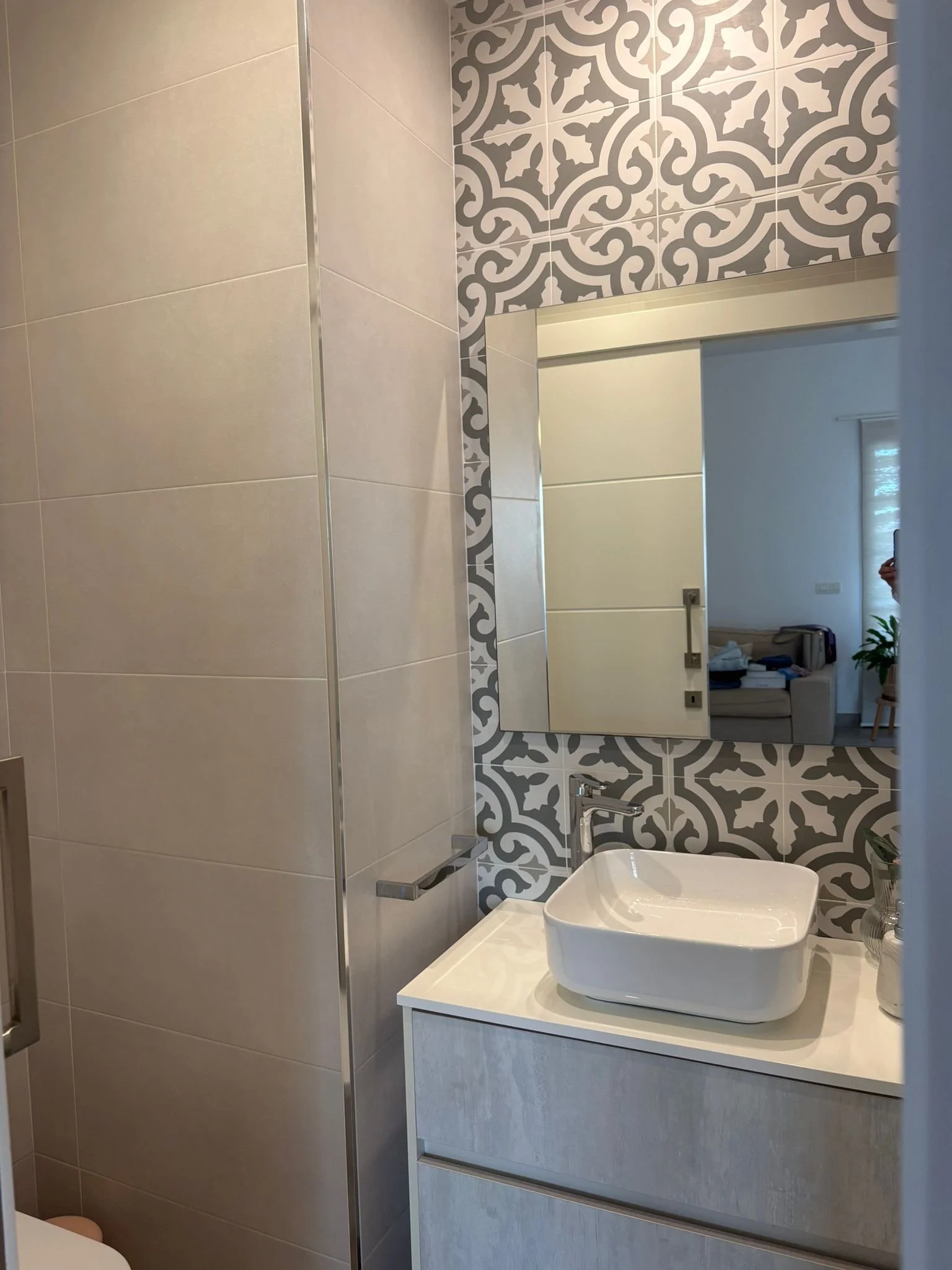 Modern bathroom with patterned tiles and a rectangular white sink on a vanity.