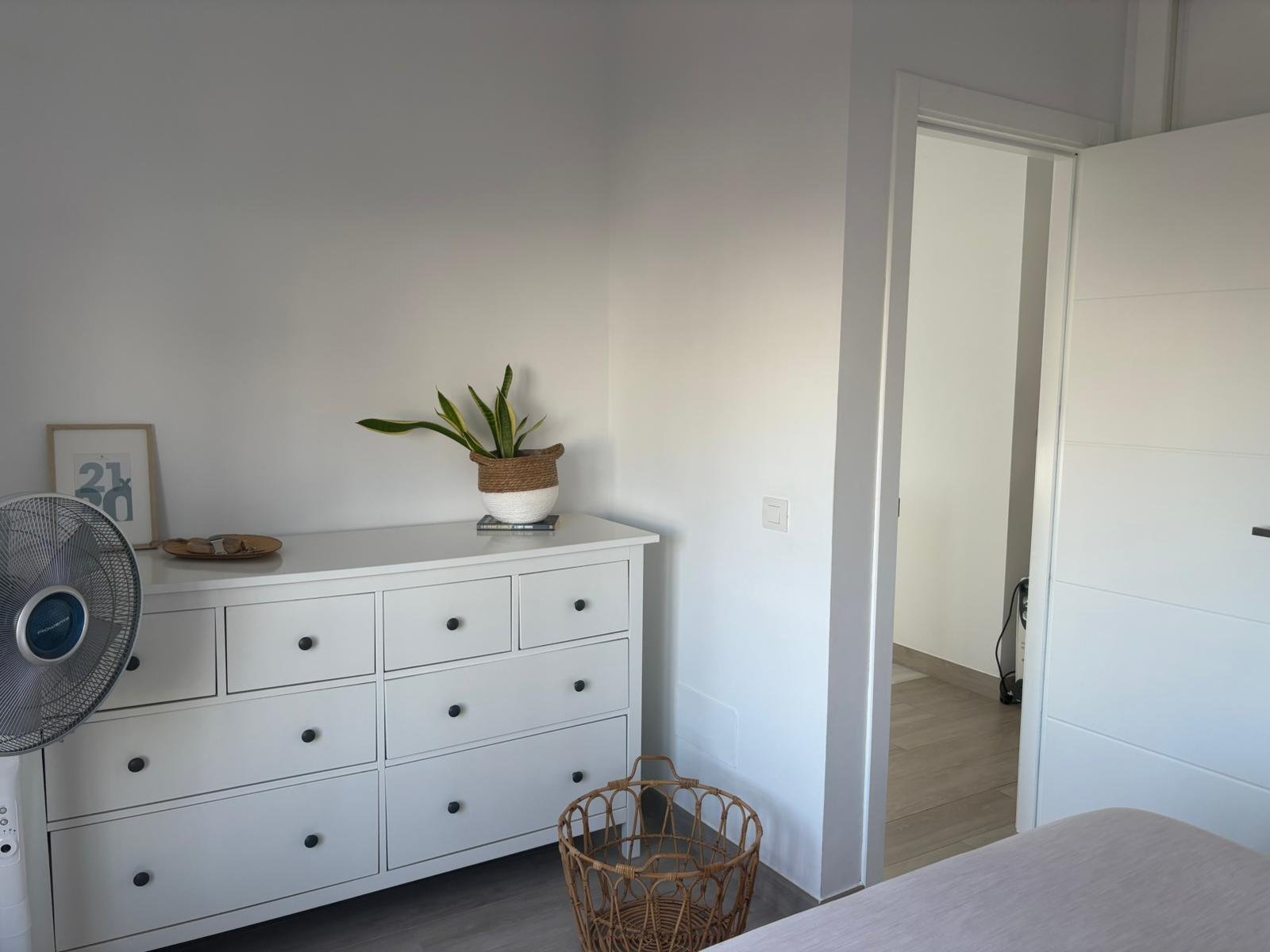 Minimalist bedroom with white dresser and potted plant