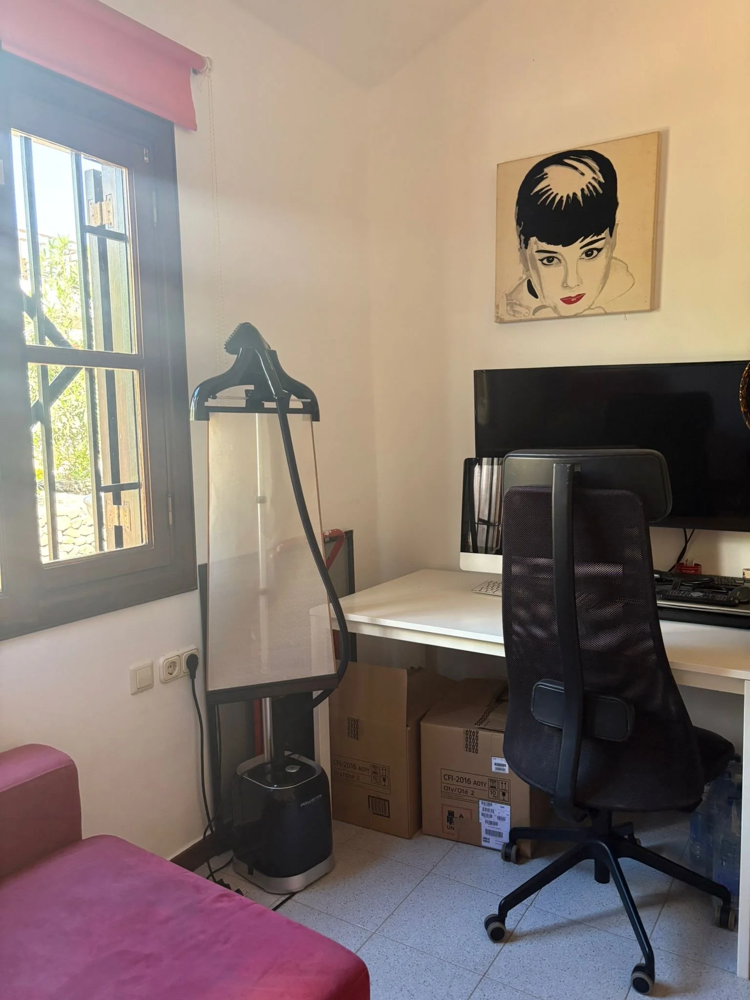 Home office setup with desk, chair, computer, and art on the wall