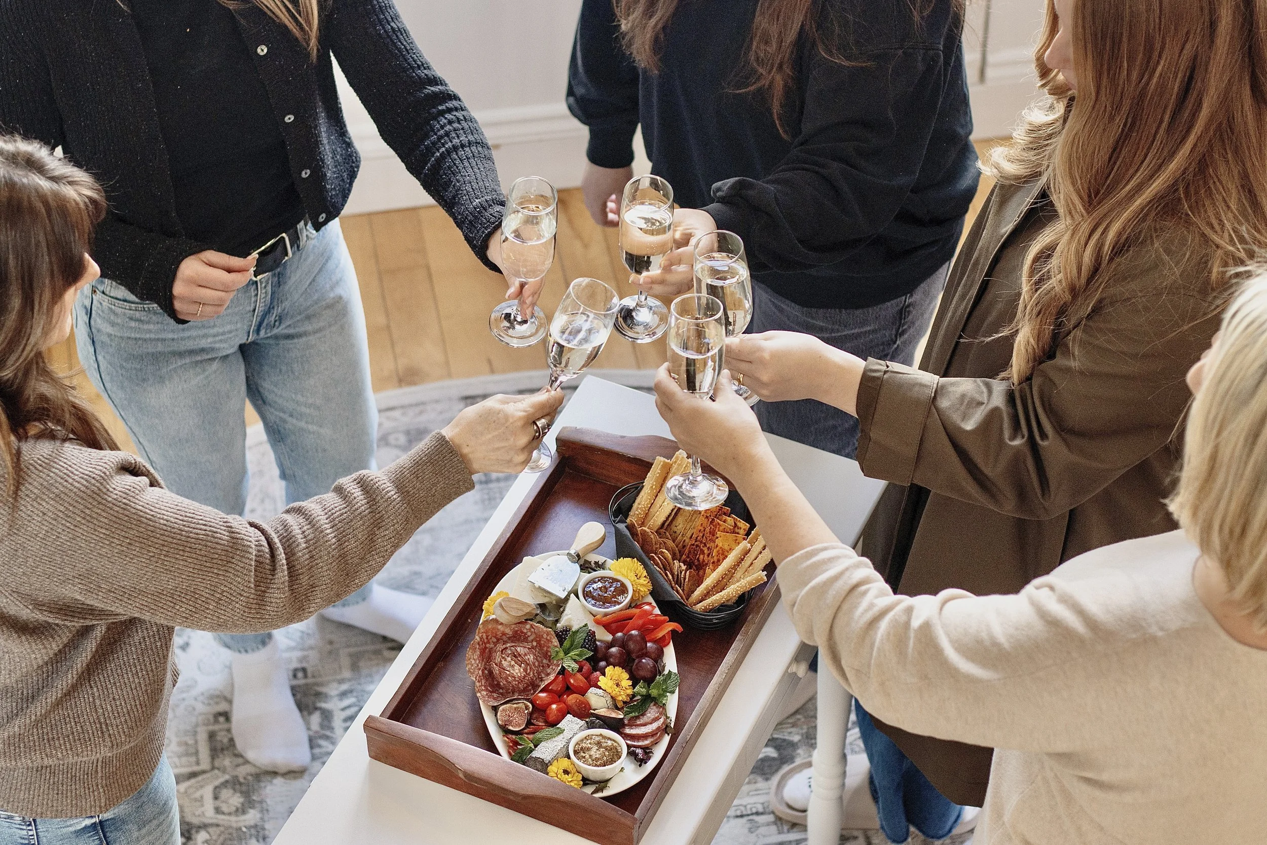 Person pouring champagne into flutes on a white surface.
