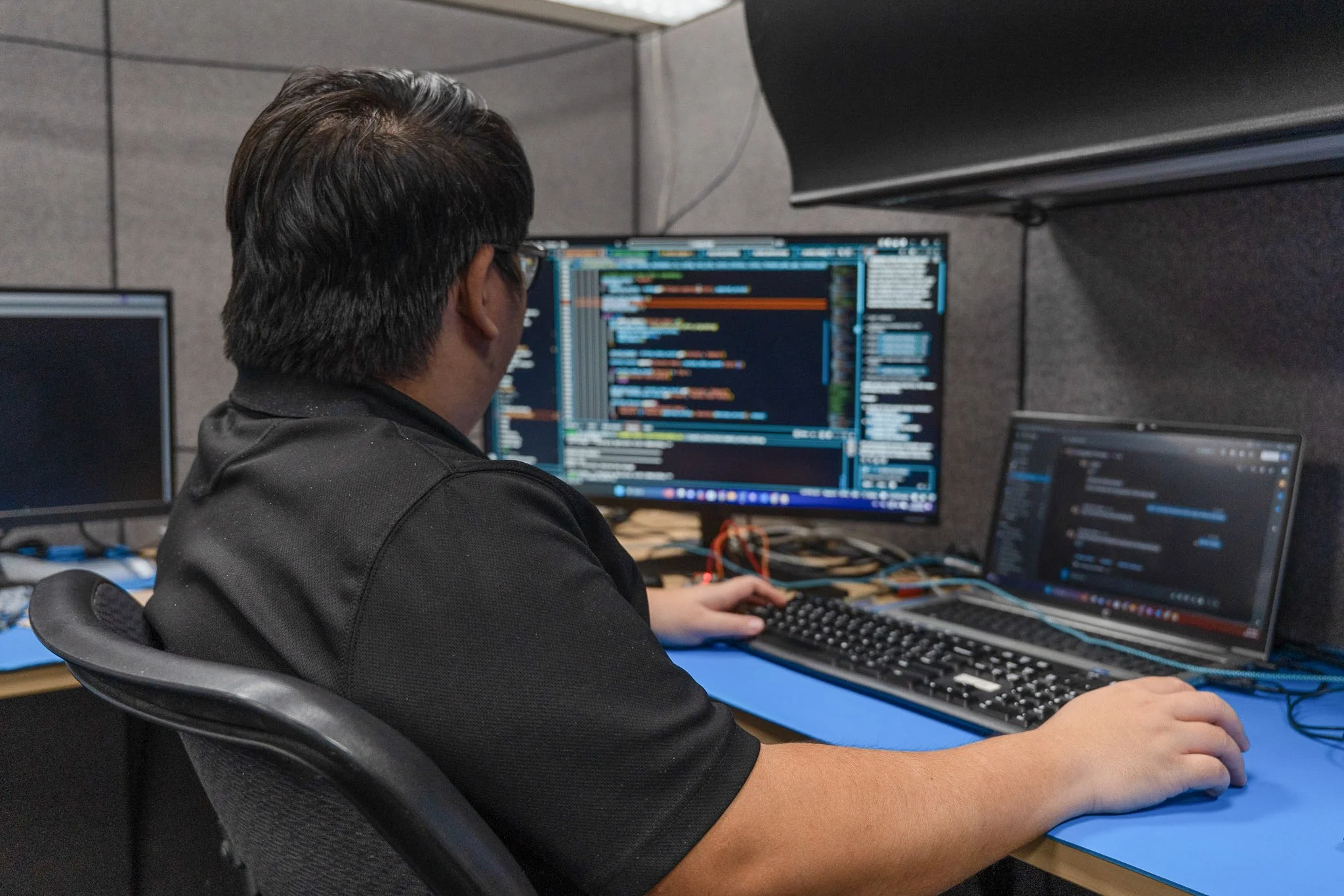 Person looking at a computer screen displaying a detailed architectural or engineering CAD drawing with various colored lines, measurements, and annotations.