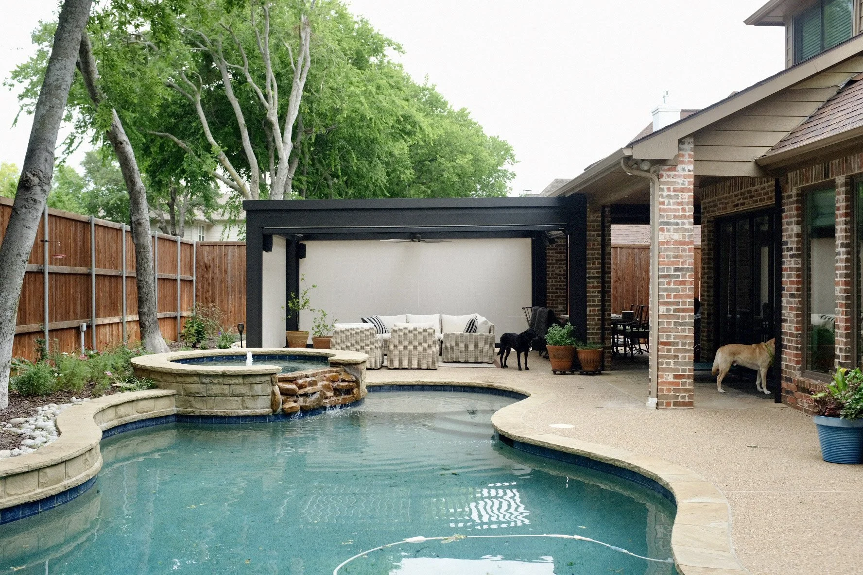 A pool view with a StruXure pergola in the distance behind the spa