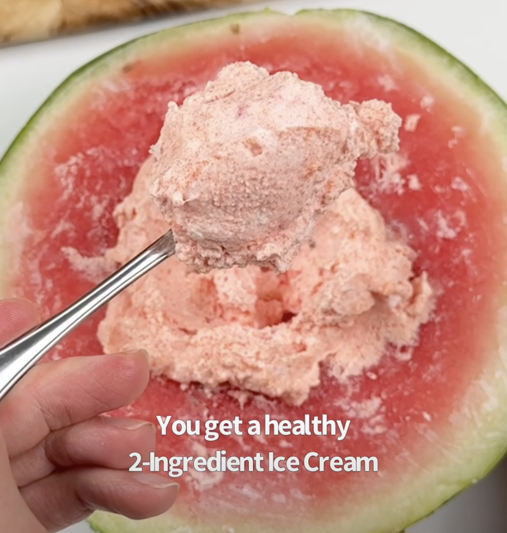 A scoop of pale pink watermelon ice cream being lifted from the frozen watermelon rind with a spoon, text overlay reads "You get a healthy 2-Ingredient Ice Cream."