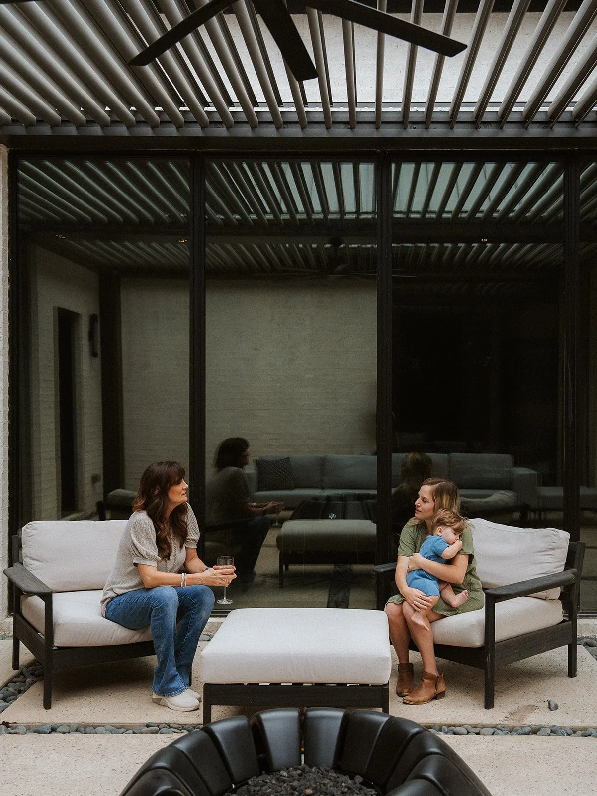 Three generations of family gathered under a StruXure Pergola X with bronze black frame and gray louvers installed by Goodlux Outdoor in Fairview Texas