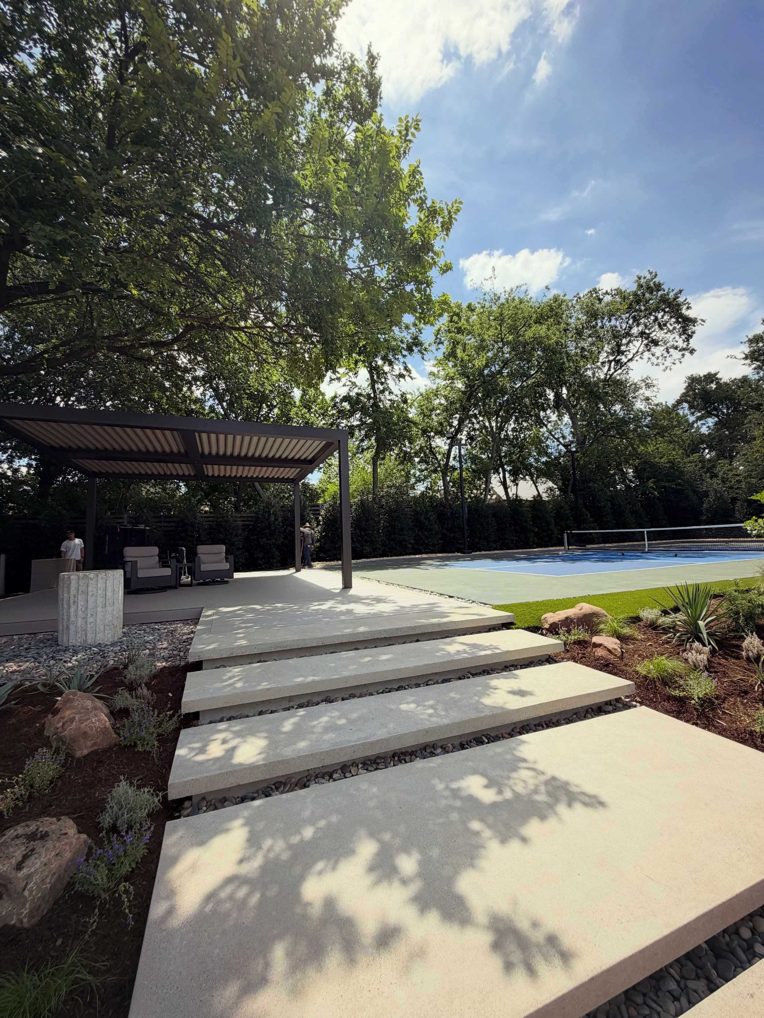 Goodlux Outdoor StruXure motorized pergola installation in Dallas-Fort Worth backyard with pickleball court, floating concrete steps, landscaping, and seating area