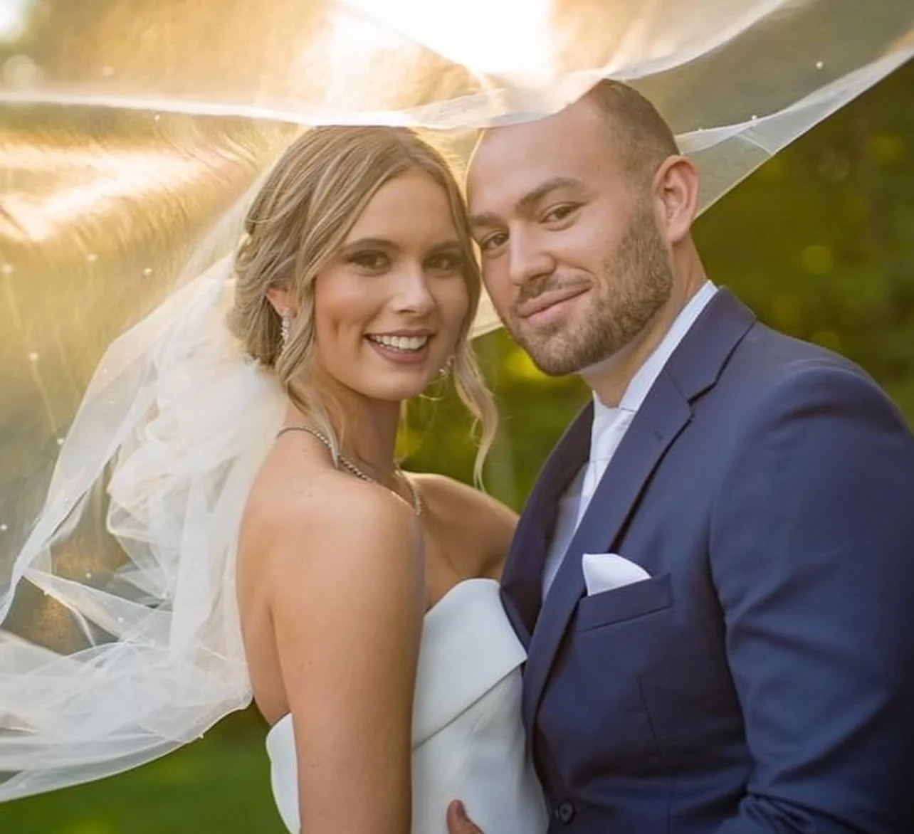 Bride and Groom on their wedding day, Bride's veil is blowing in the wind at sunset
