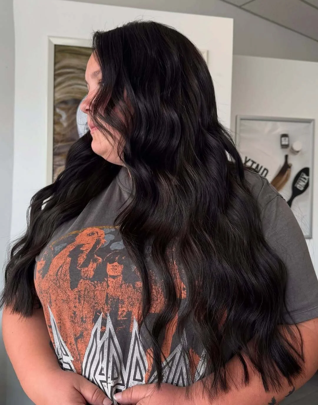     Long dark brunette hair extensions styled in soft waves for added length, shine, and fullness at Studio H.