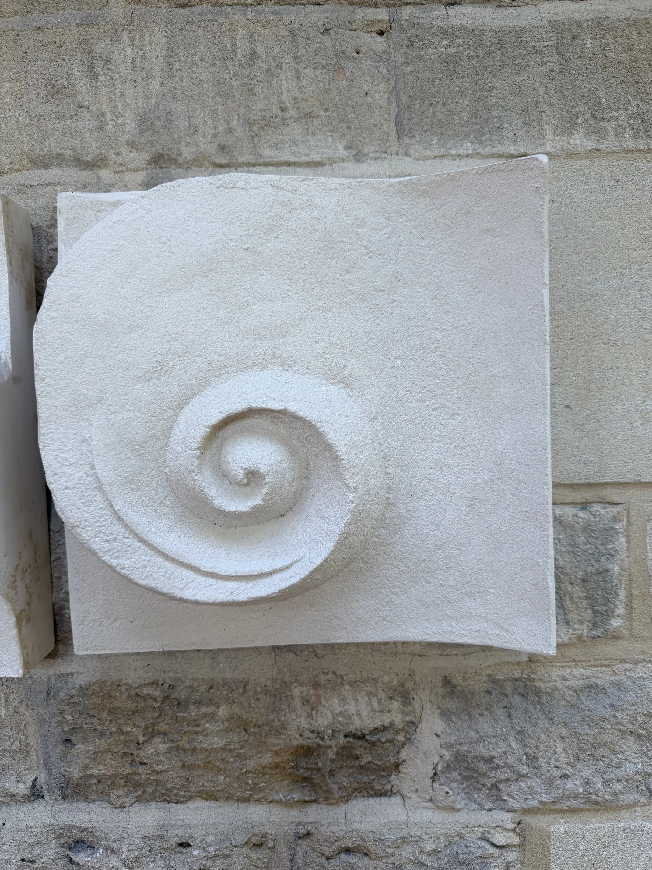 Wave Phase White Wall Sculpture seen at an angle, showing the panel standing off the stone wall