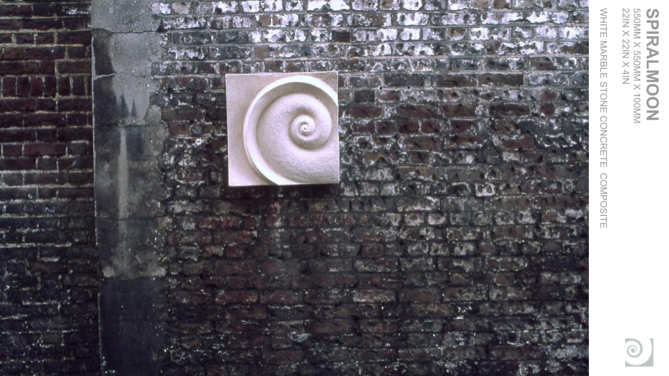 A white marble spiral shell sculpture mounted on a brick wall.