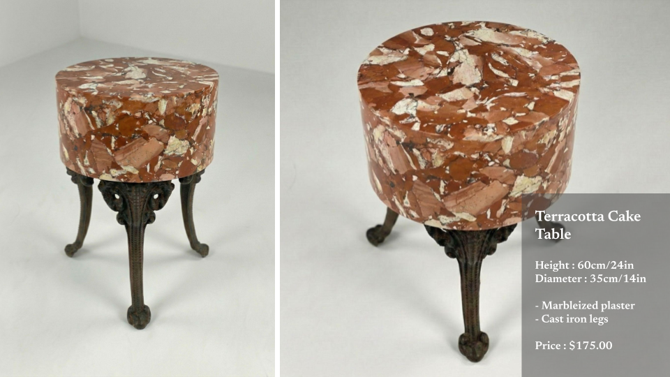A small, ornate table with a round terracotta cake-style top made of marbleized plaster and cast iron legs.