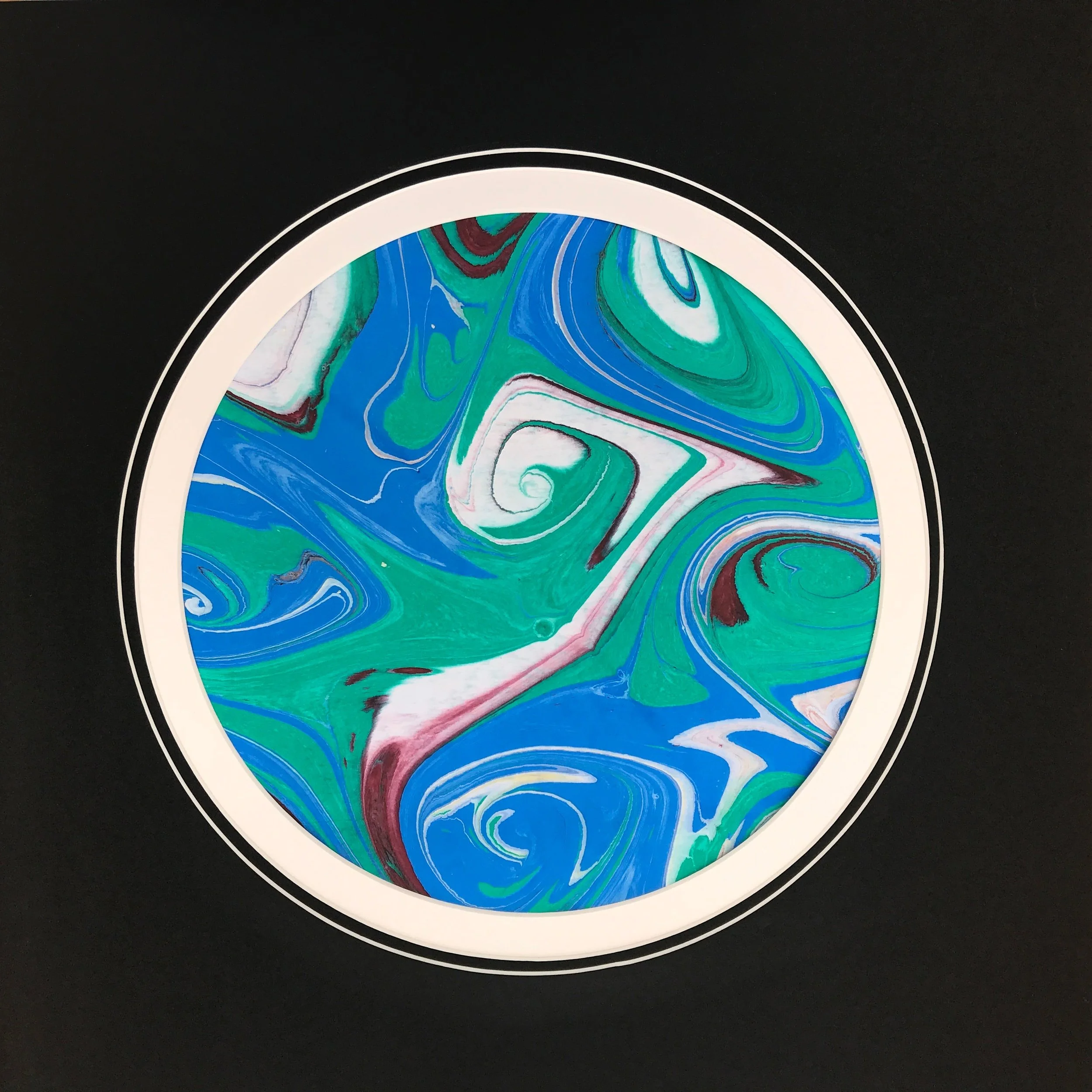 Green Marbled Moon print with a white rim, its green and blue marbling set against black