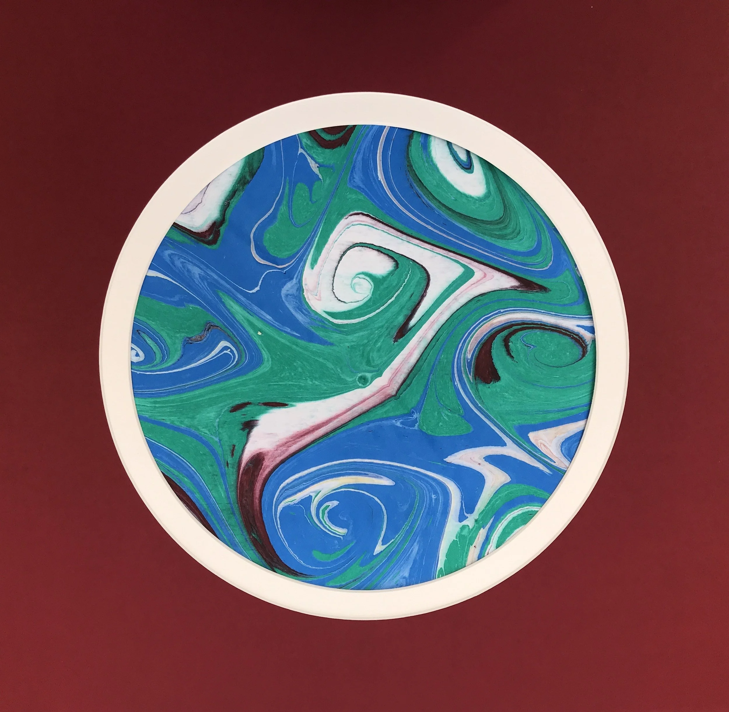 Green Marbled Moon print with a white rim, shown against a deep red ground
