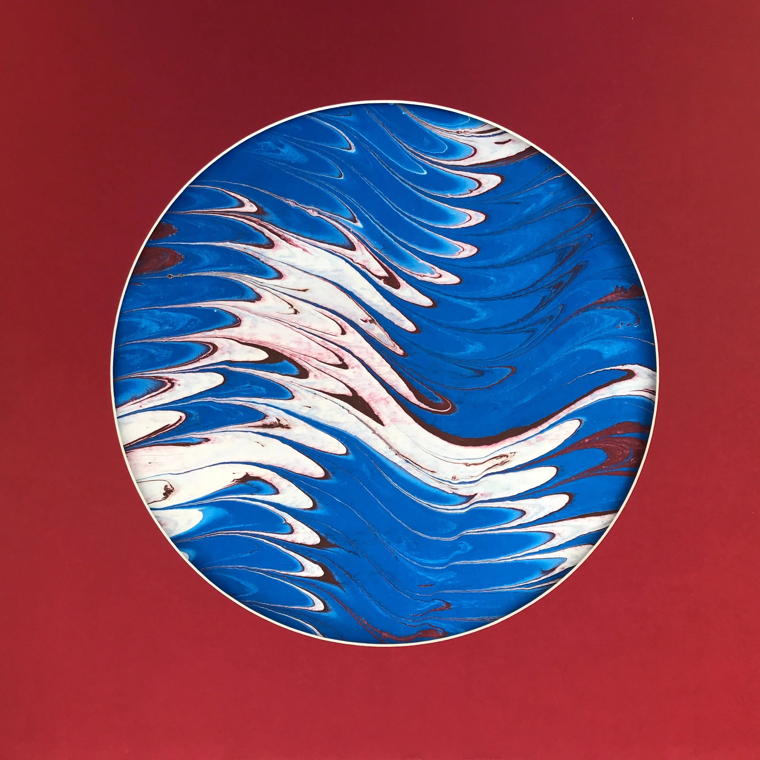 Watery Marbled Moon print, a circular marbled disc of blue and white feathered swirls on a deep red ground
