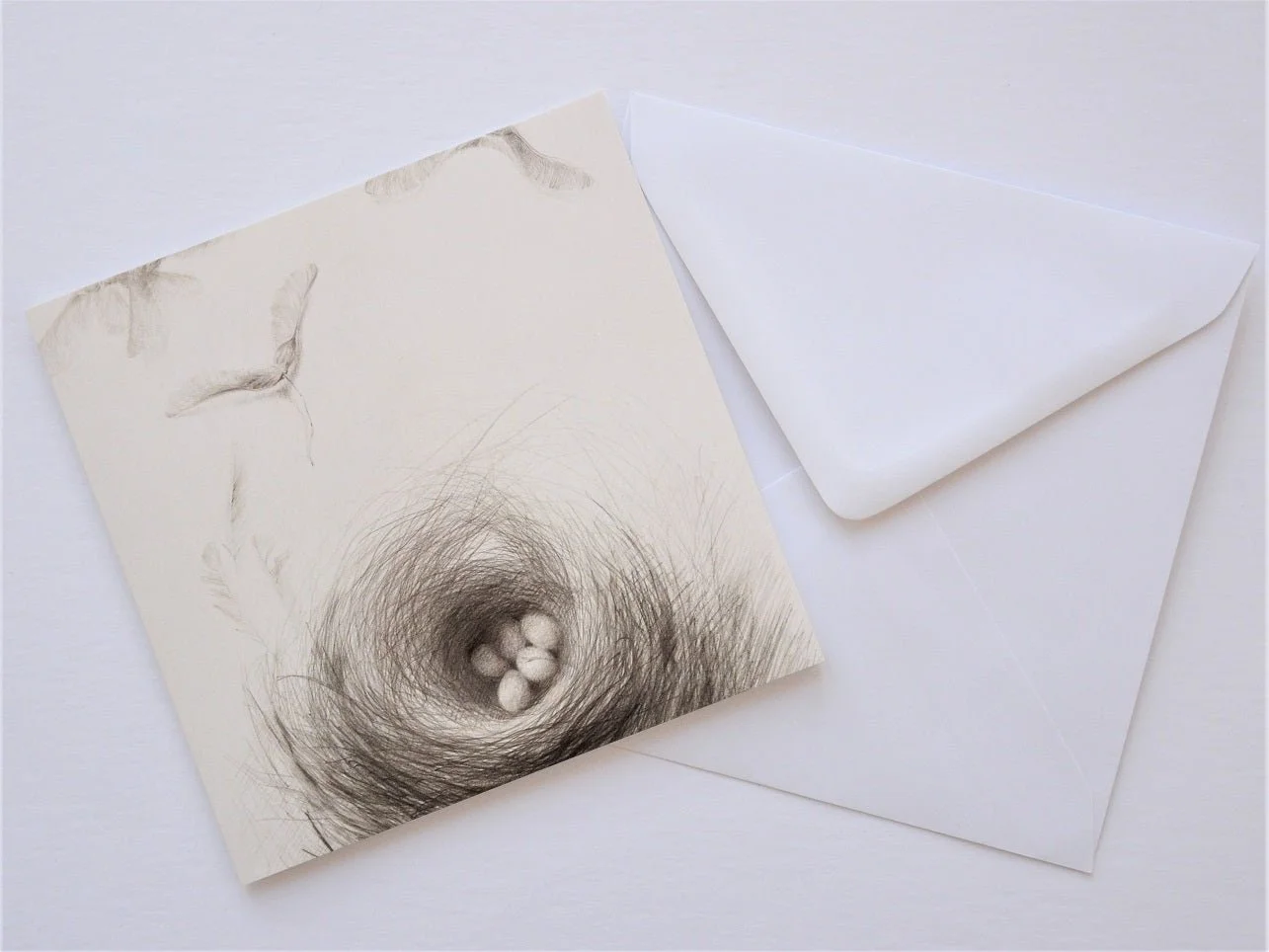 Nested Sycamore Seeds greetings card shown at an angle with its white envelope