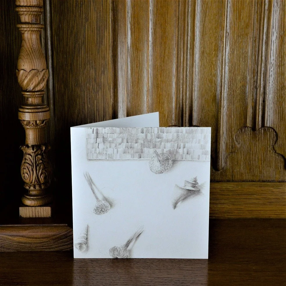 Woven Watsonia Shells greetings card standing on a wooden mantelpiece